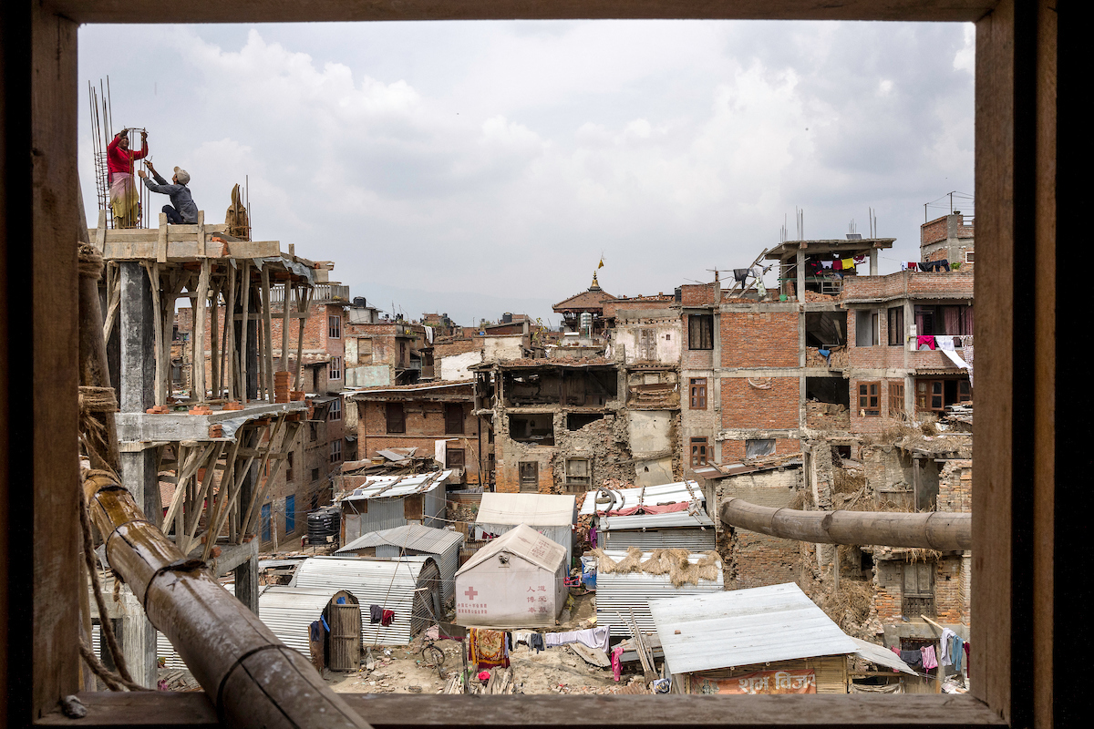 Workers are seen through the window of a building in construction in a square in Bhaktapur, Nepal