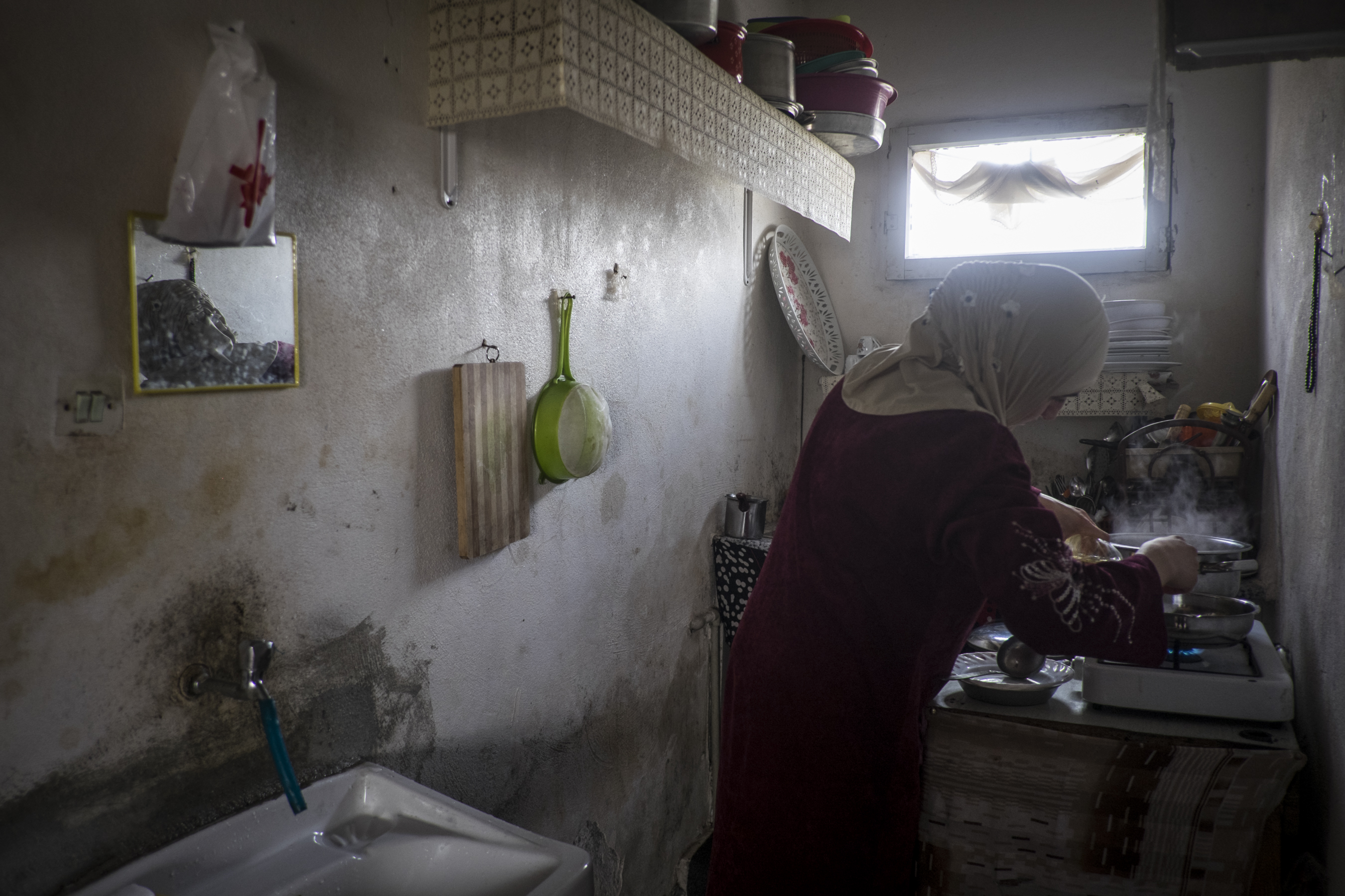 A woman cooks in a basement flat