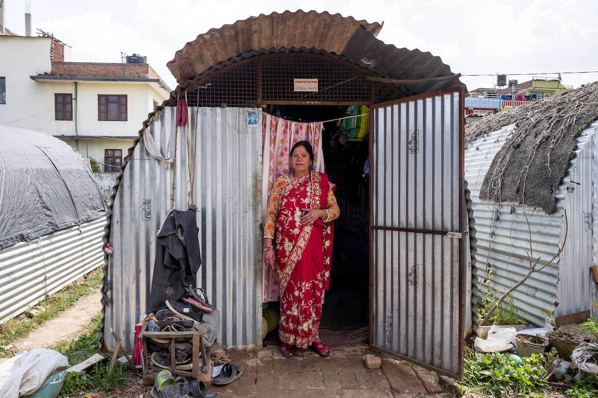 Hira Devi, 50, stands outside her temporary shelter in Harisiddhi, Nepal