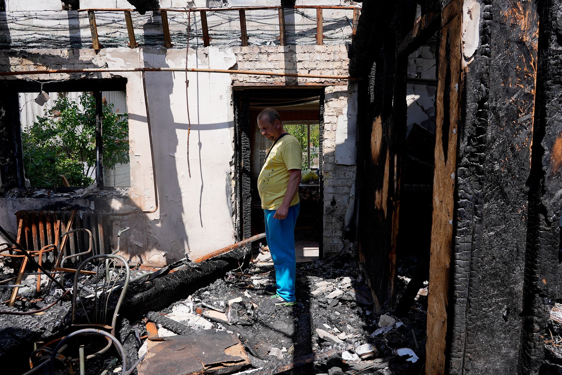 Vadym Zherdetsky stands inside his destroyed home in Moschun village looking at the wreckage. His house was hit by missiles in February.