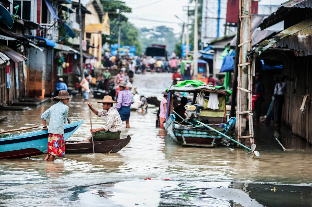 People wade and paddle through flooded streets on the outskirts of Pathein, in the Irawaddy delta of Myanmar.