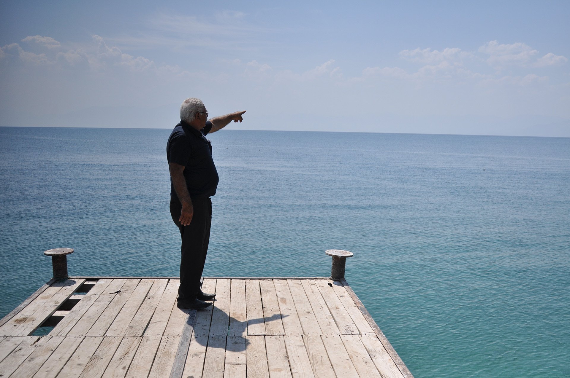 Mustafa Abali, the head of Çitören, near Van, stands near the end of a dock and points to the scene of the shipwreck in which 61 people died (not pictured).