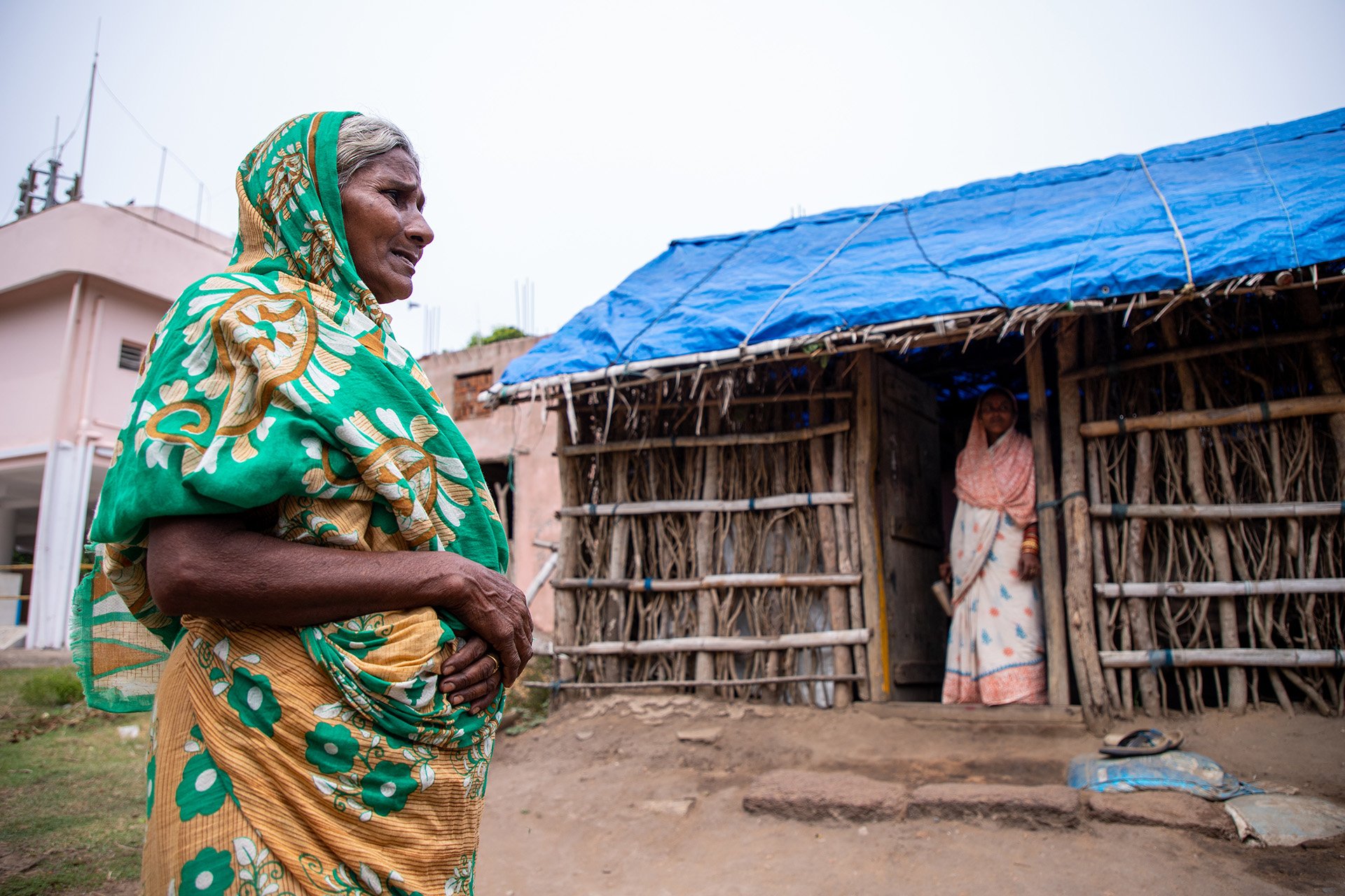 A Dalit woman standing outside her house, which has a blue tarpaulin roof, typical of Dalit houses in Narasinghpatana, in the eastern state of Odisha, where many are still awaiting government compensation three years after disaster struck.