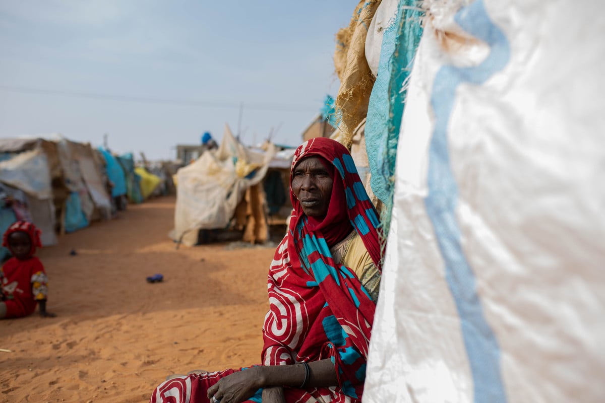 A woman sits outside a tarped tent in West Darfur, Sudan.