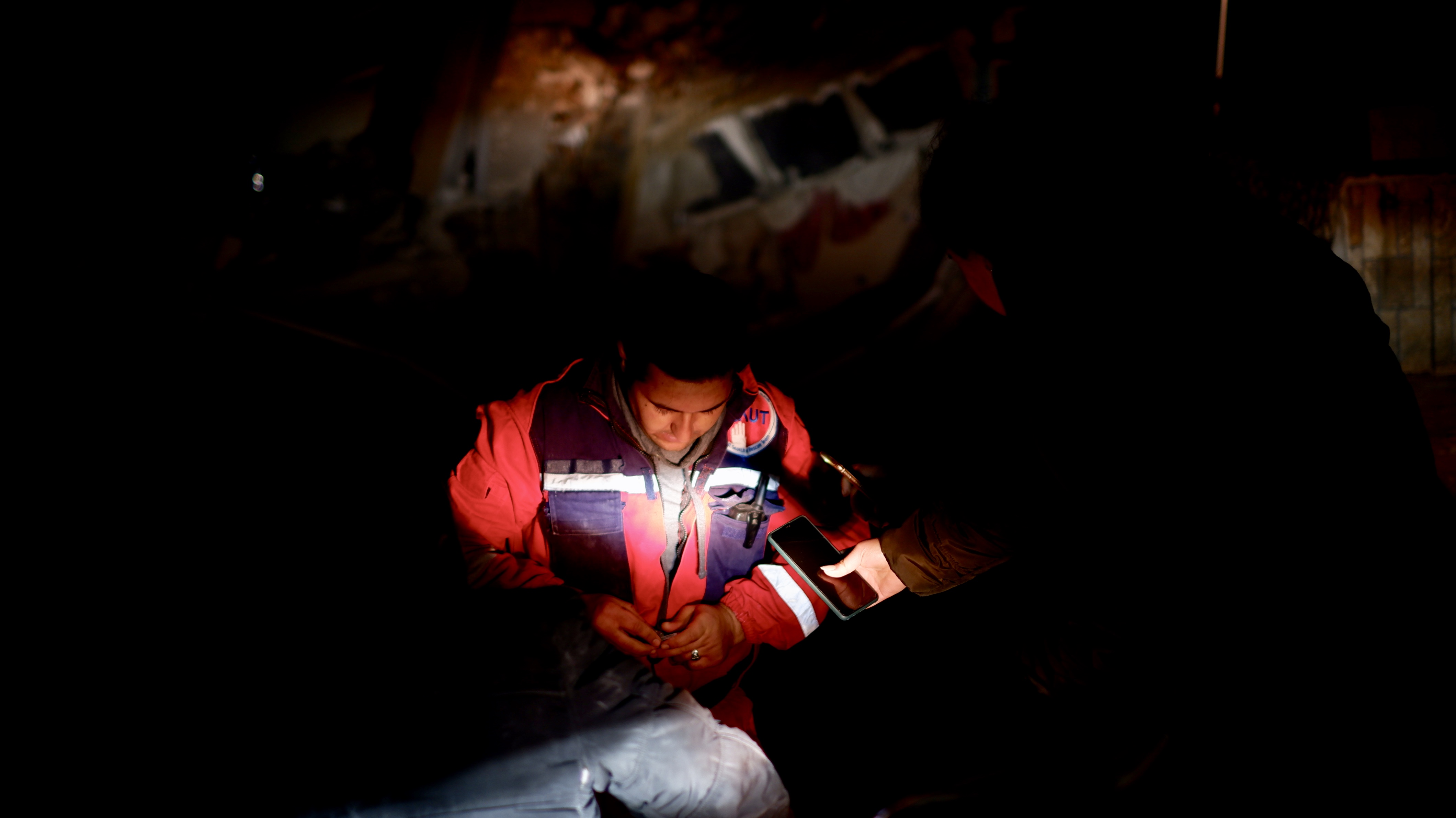 It's night time. A rescue worker stands near wreckage in Antakya, Turkey.