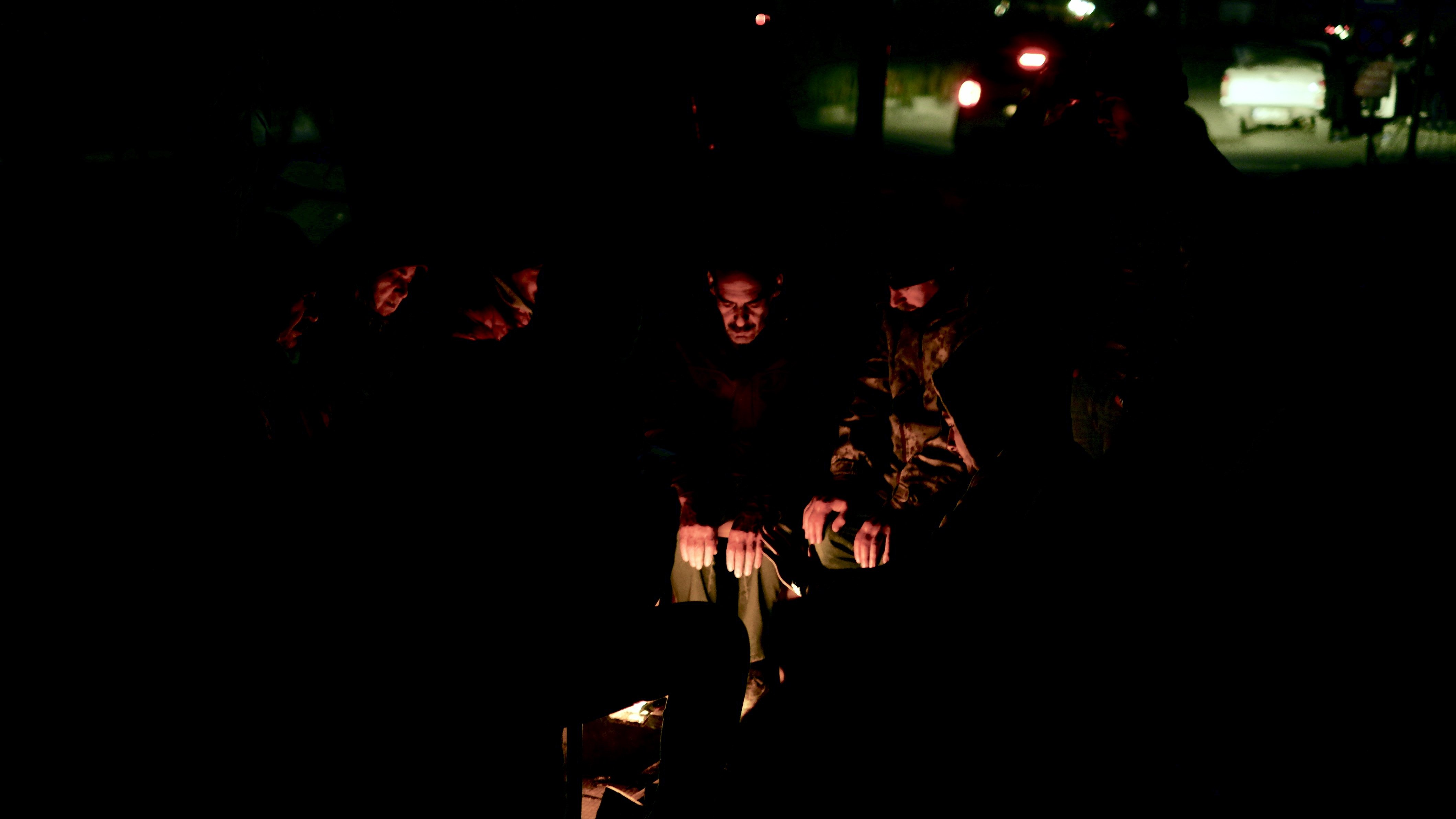 It's nighttime. Earthquake victims huddle around a makeshift fire in Antakya, southern Turkey, which was hit hard by the earthquakes, on 7 February 2023