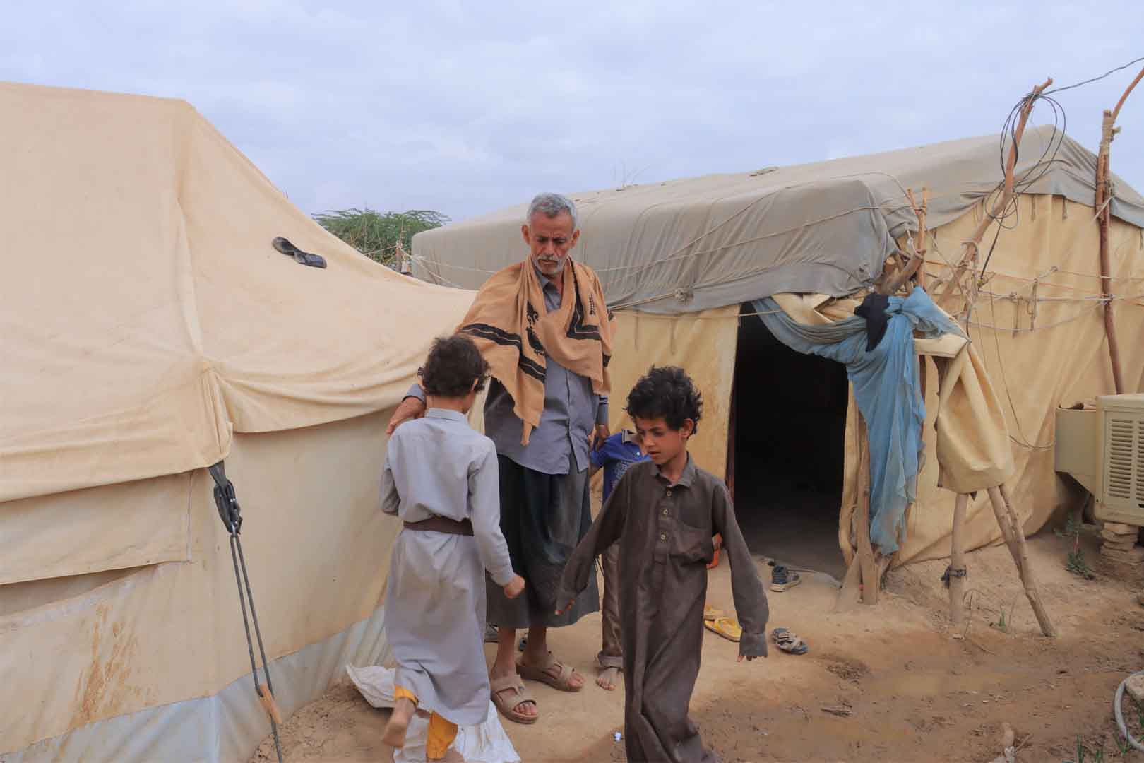 Abdullah al-Jaradi and two of his sons outside a tent in Sailat al-Rumaila camp in Marib, Yemen 28 January 2023