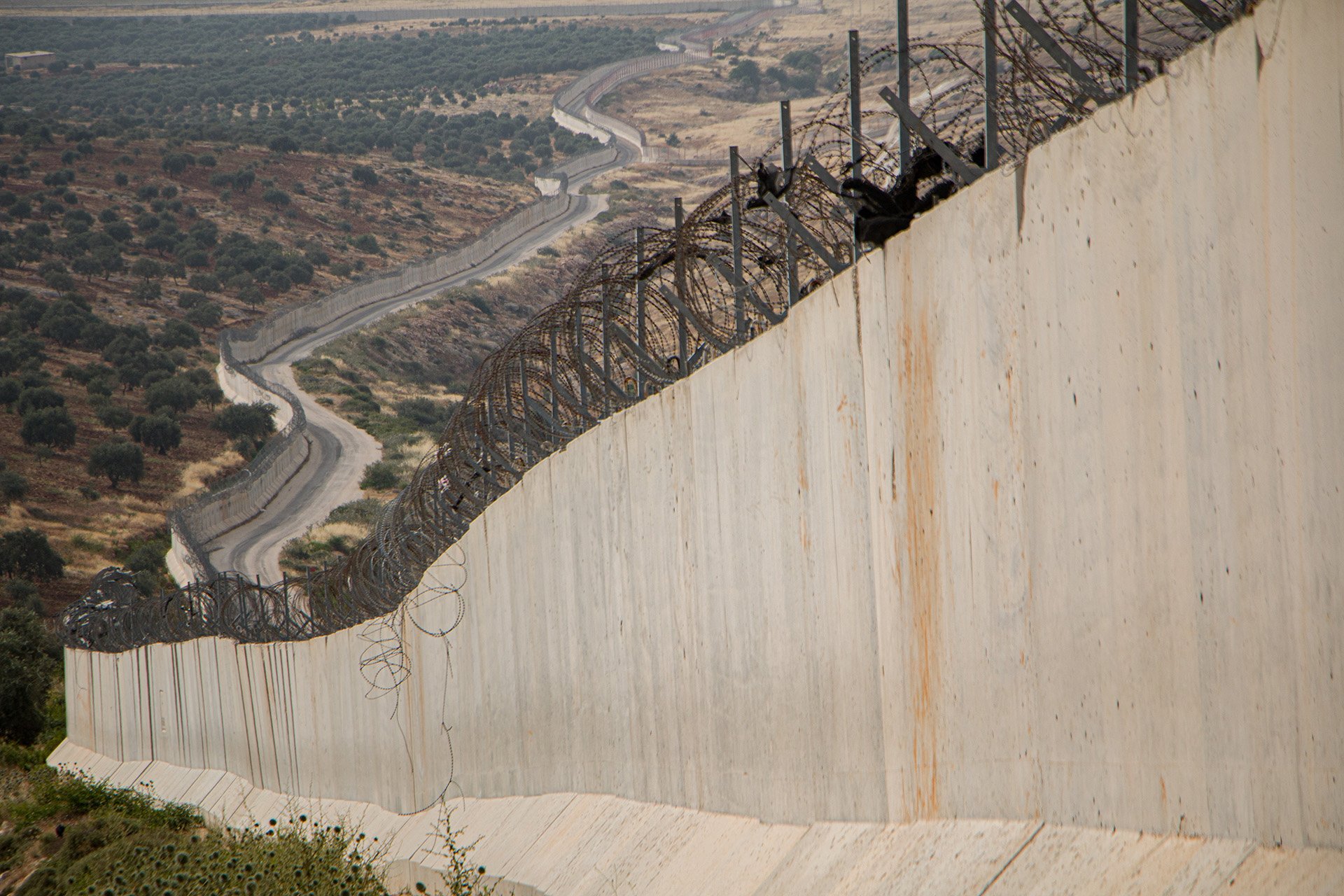 A concrete wall with barbed wire on top stretches into the distance.