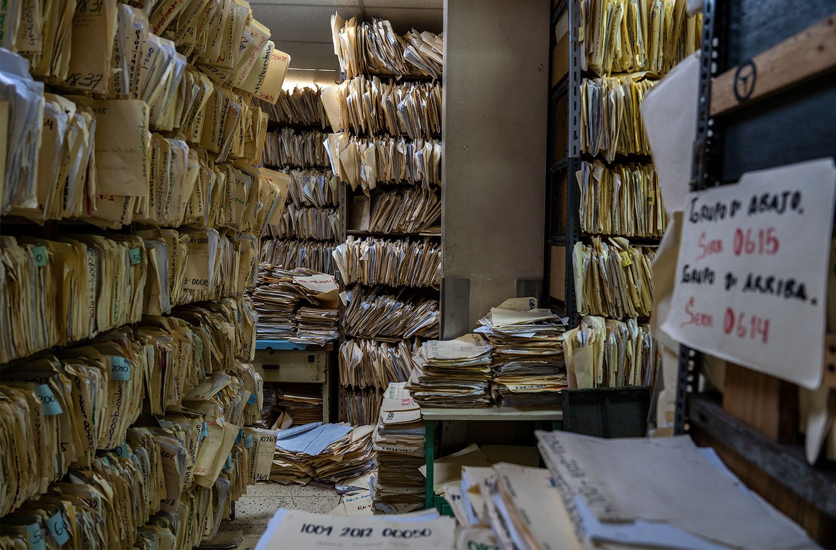 This is a picture from the inside of an office in the Hospital Escuela in Honduras. Inside are rows and rows of paperwork in manila folders that are placed in bookshelves.