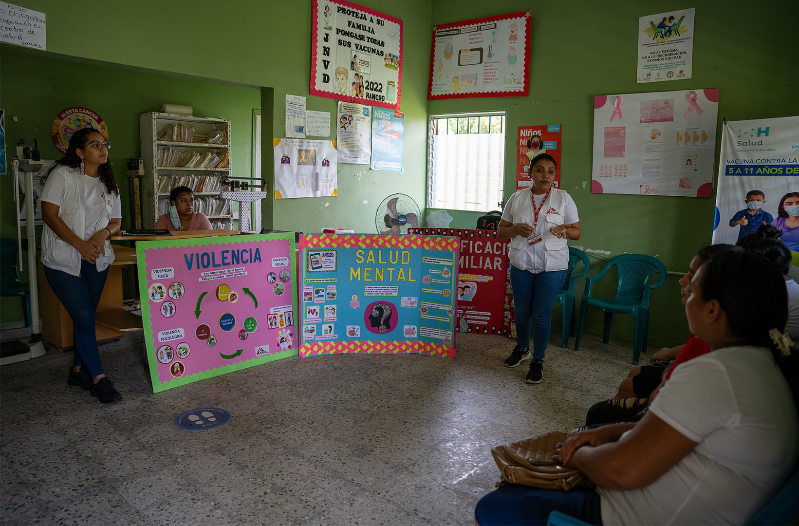 A person is giving a presentation on violence and mental health. They have bright posters with information on these two topics.