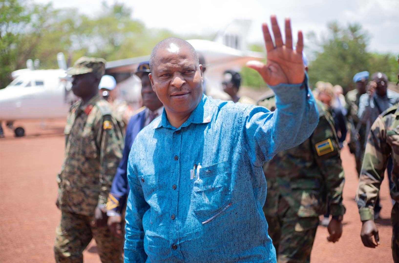 This is a photo of Faustin-Archange Touadéra, president of Central African Republic. He is pictured waving his right hand. Behind him are military forces.