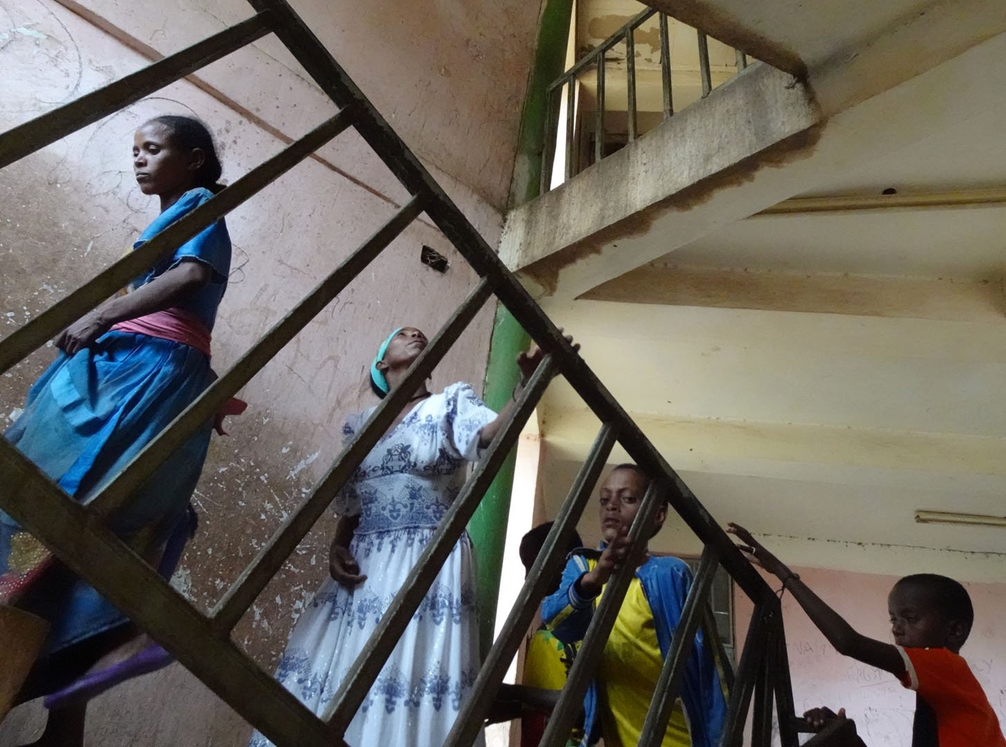 A group of people walk up a set of stairs, we see them from a low angle.