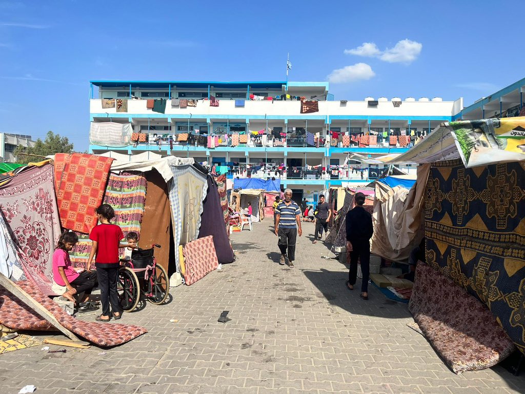 This photo shows the outside of a school in Central Gaza that has become refuge for people escaping the war. The outside of the school is full of tents.