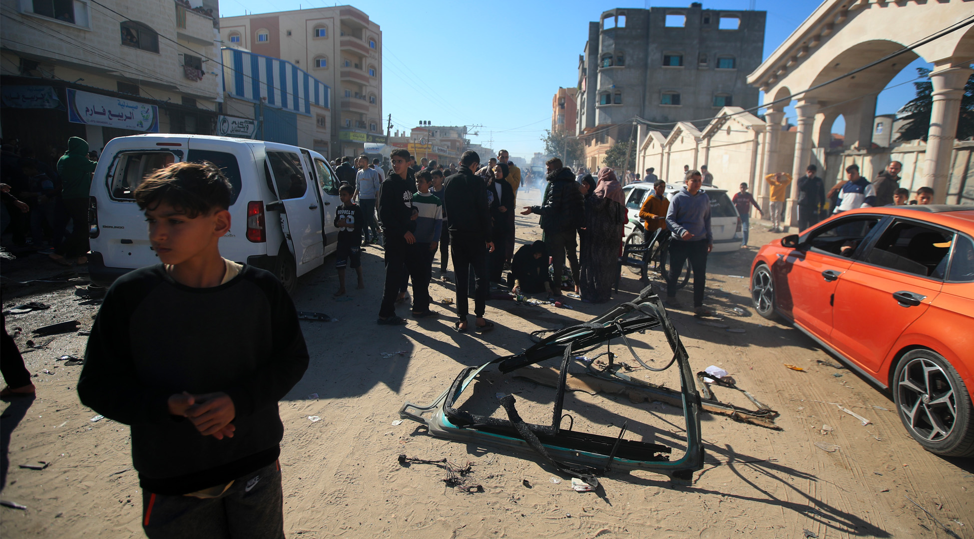 A crowd gathers around the wreckage of the car journalists Hamza al-Dahdouh and Mustafa Thuraya were travelling in when it was hit by an Israeli airstrike.