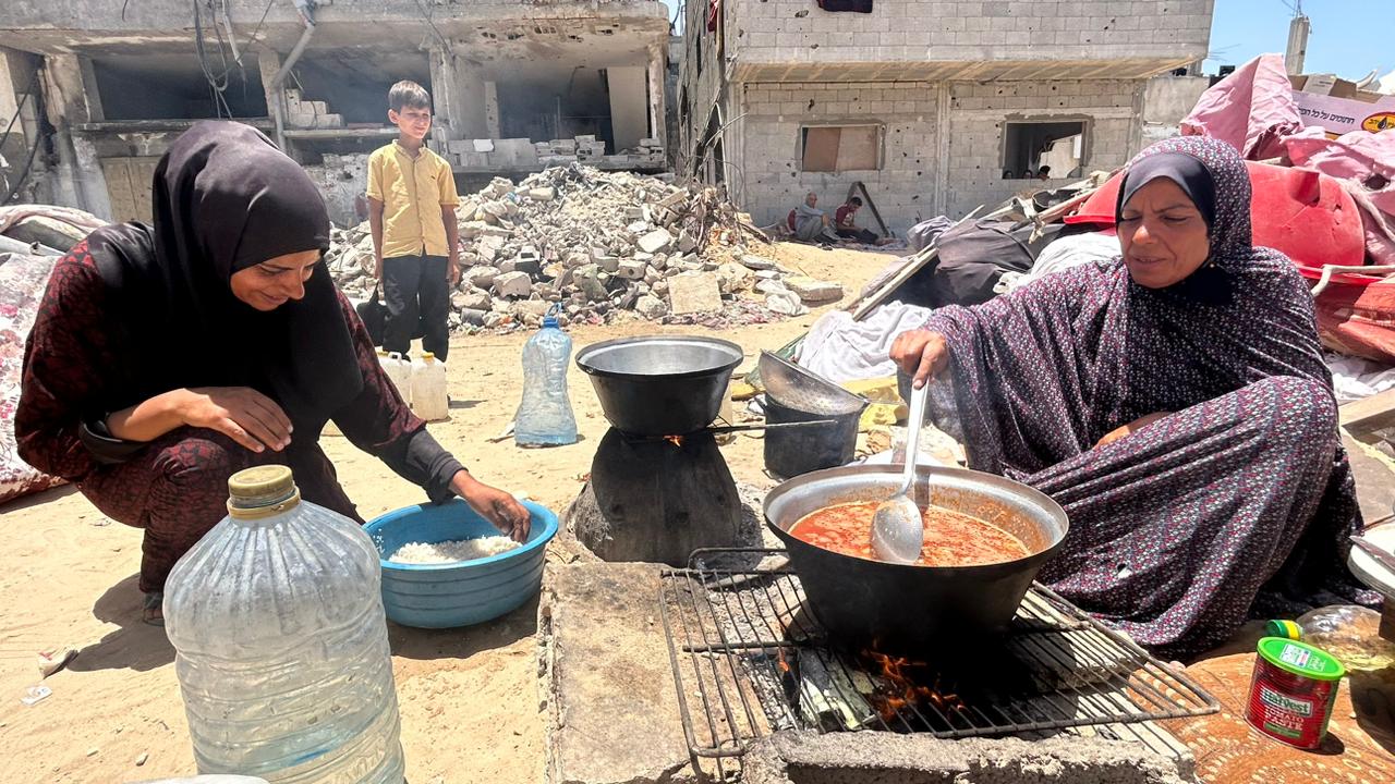 Naeema al-Ashour (right) sits on the ground next to another woman bothcooking outside the remnants of her destroyed home in June. She was killed by an Israeli missile strike in the same location in August.