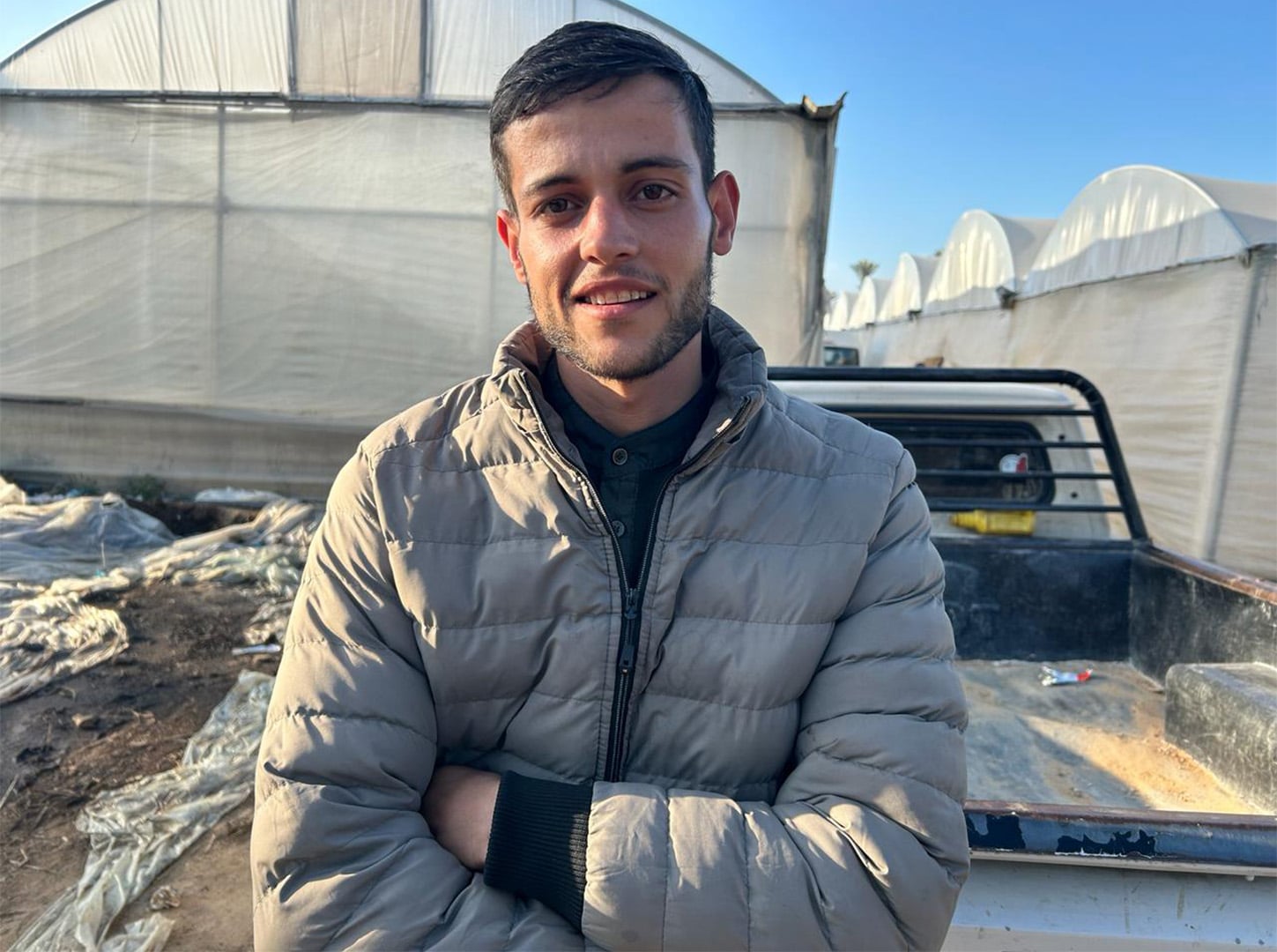 A photo of Ahmed Abu Nahia taken in January. He stands with his arms crossed, wearing a jacket and smiling. He was killed in an Israeli airstrike in July.