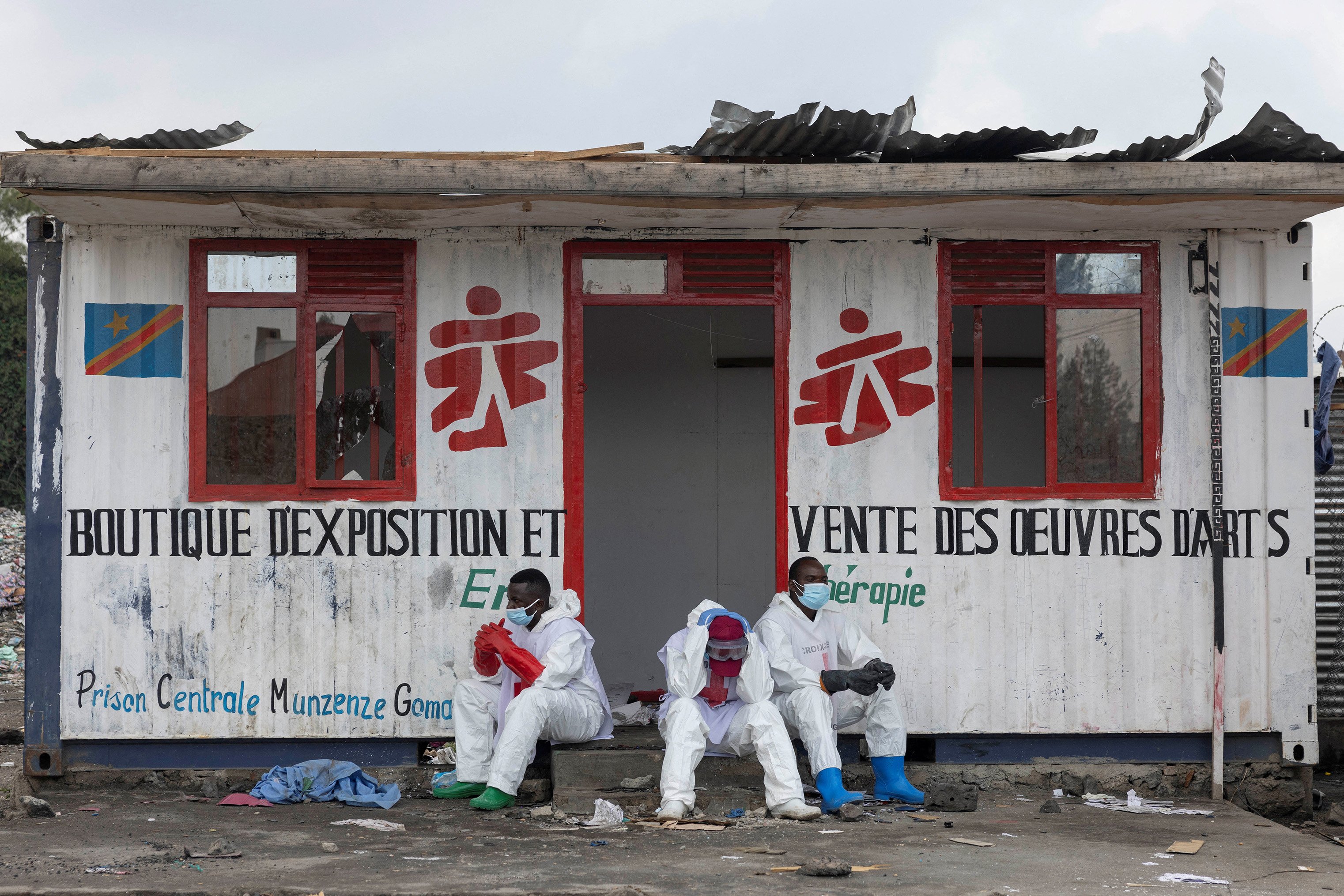 Red Cross volunteers wearing HAZMAT suits sit and wait in front of a container booth for a truck carrying the bodies of victims who died in a jailbreak and fire at a prison in Goma, which was seized by M23 rebels and Rwandan troops in late January.