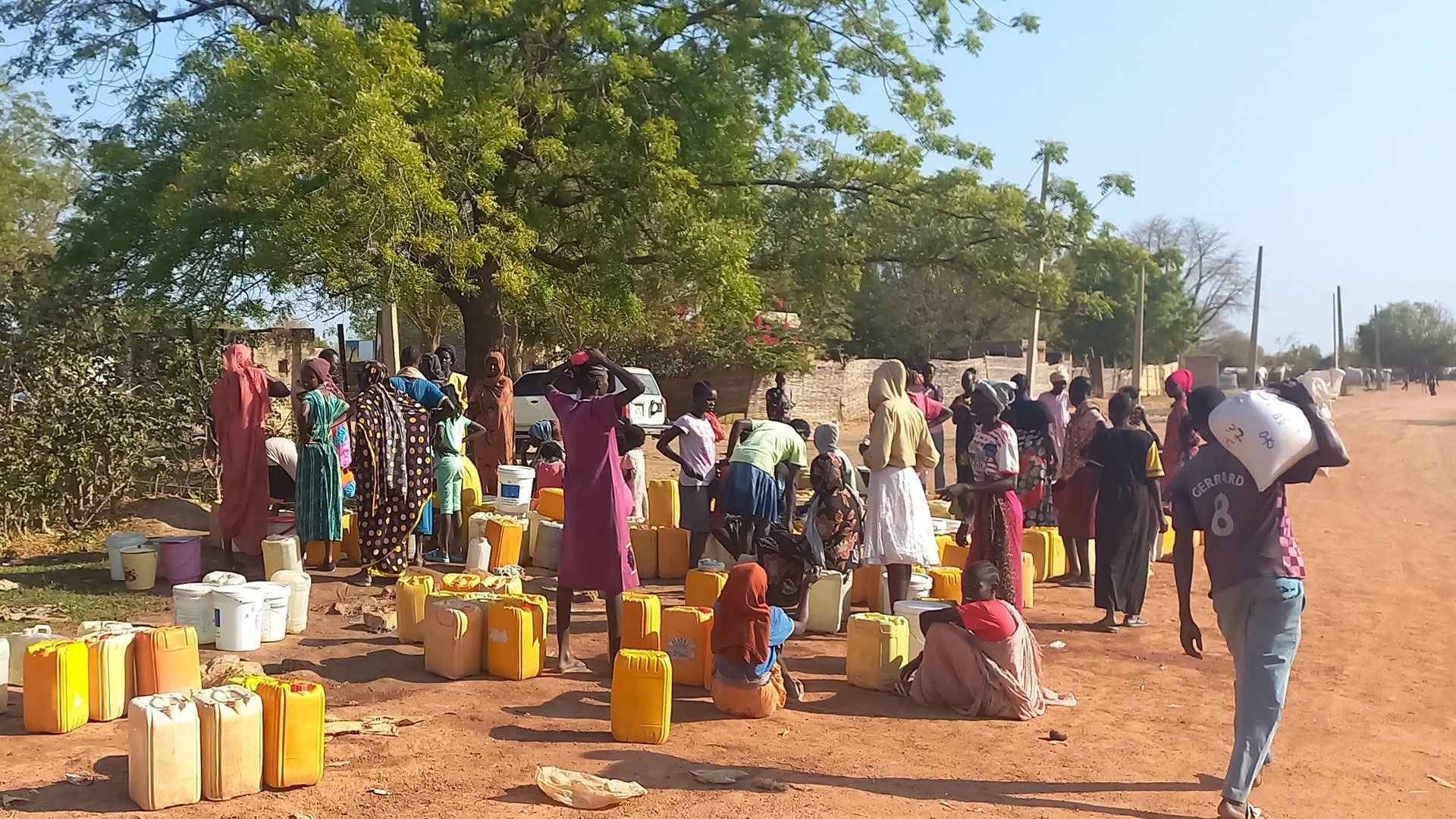 Residents of Abyei town gather at a water point and take shade under a tree. The arrival of displaced people from Sudan has strained local infrastructure in the disputed region. 