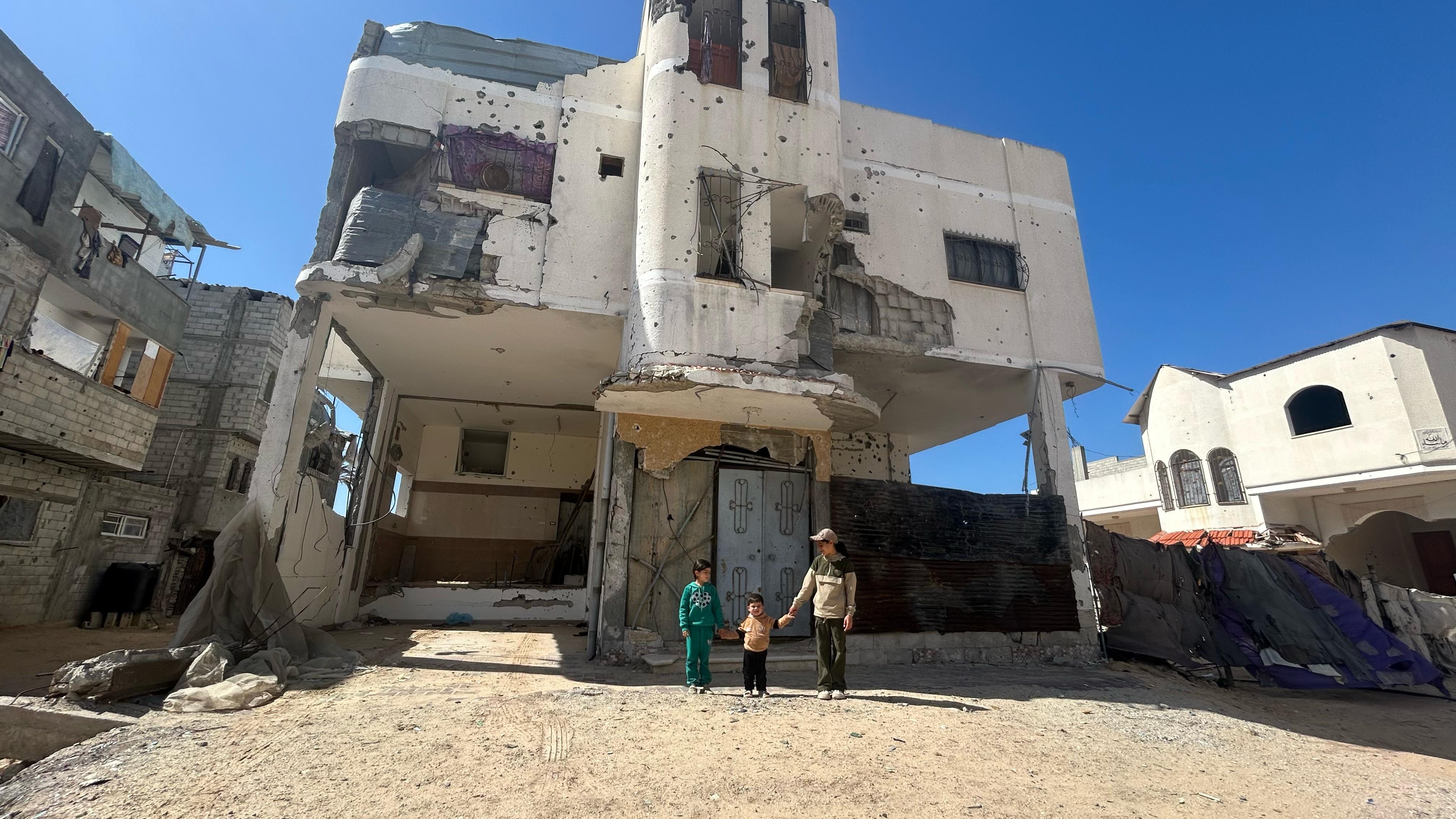 Three of Mohamed al-Astal's children in front of their partially destroyed home in Khan Younis, Gaza.