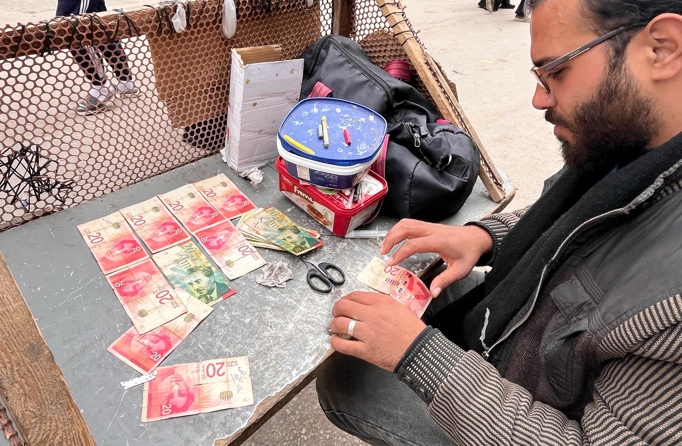 Ahmed al-Jayeh, 29, fixing worn-out bills at a stall he set up in Deir al-Balah's market.