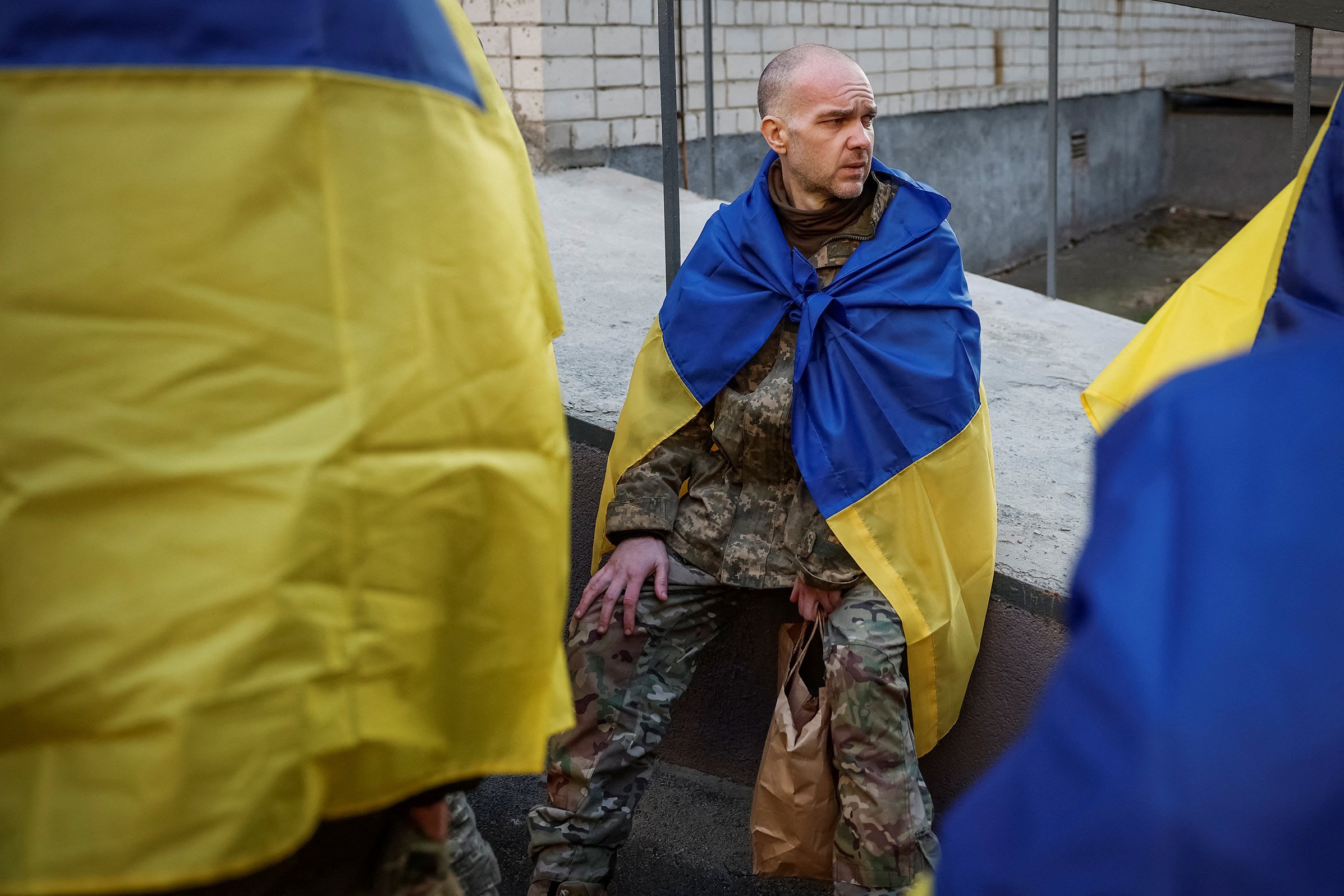 A Ukrainian prisoners of war (POW) returns after a swap. He wears the Ukrainian flag over his shoulders.