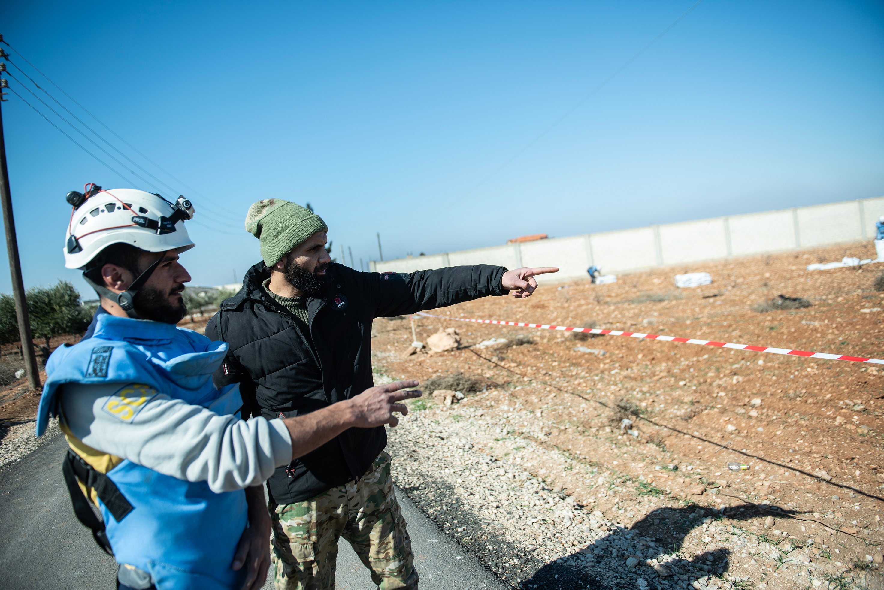 Al-Mohammed is shown pointing out into a field at the cluster bombs he spotted.
