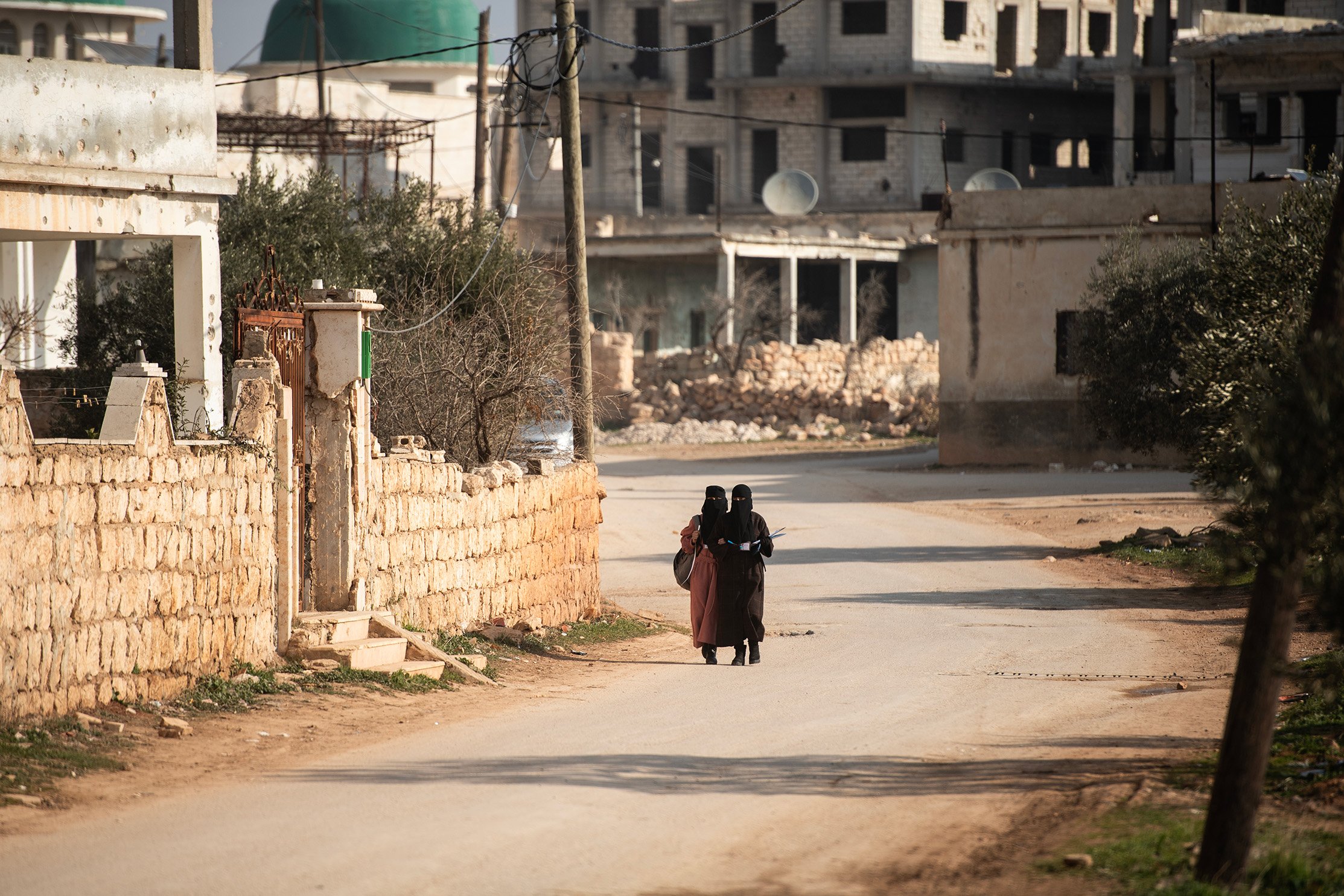 Two women walk down a road in al-Nayrab, Syria.