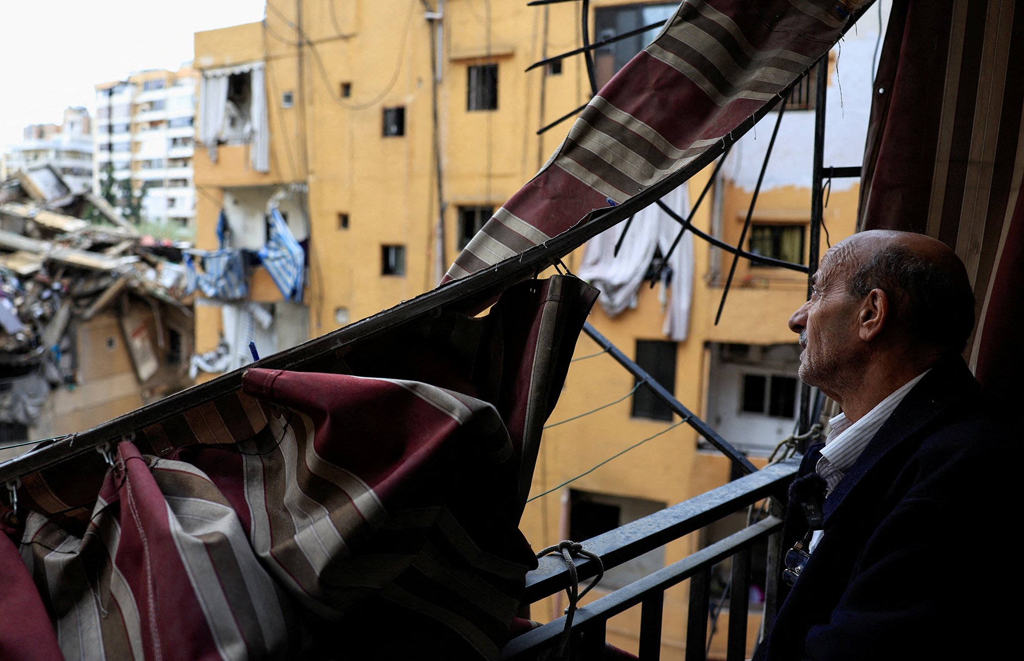 Zahi Hijazi looks out from the balcony of his damaged apartment in Beirut’s southern suburbs, after returning home from displacement following the November 2024 ceasefire between Israel and Hezbollah.