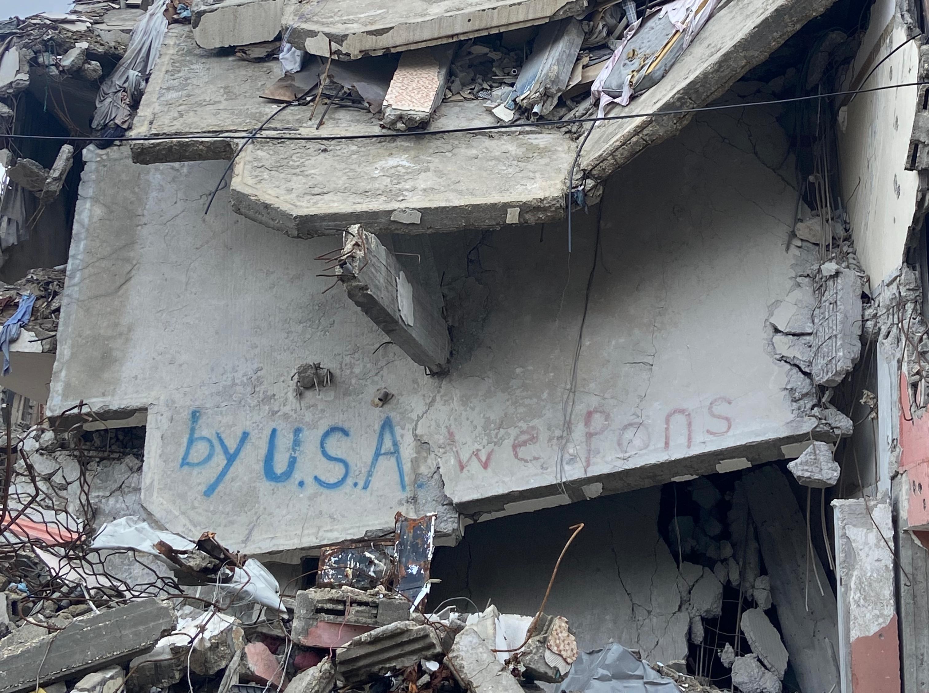 Grafitti on the remains of a destroyed building in Gaza that reads: By USA weapons.