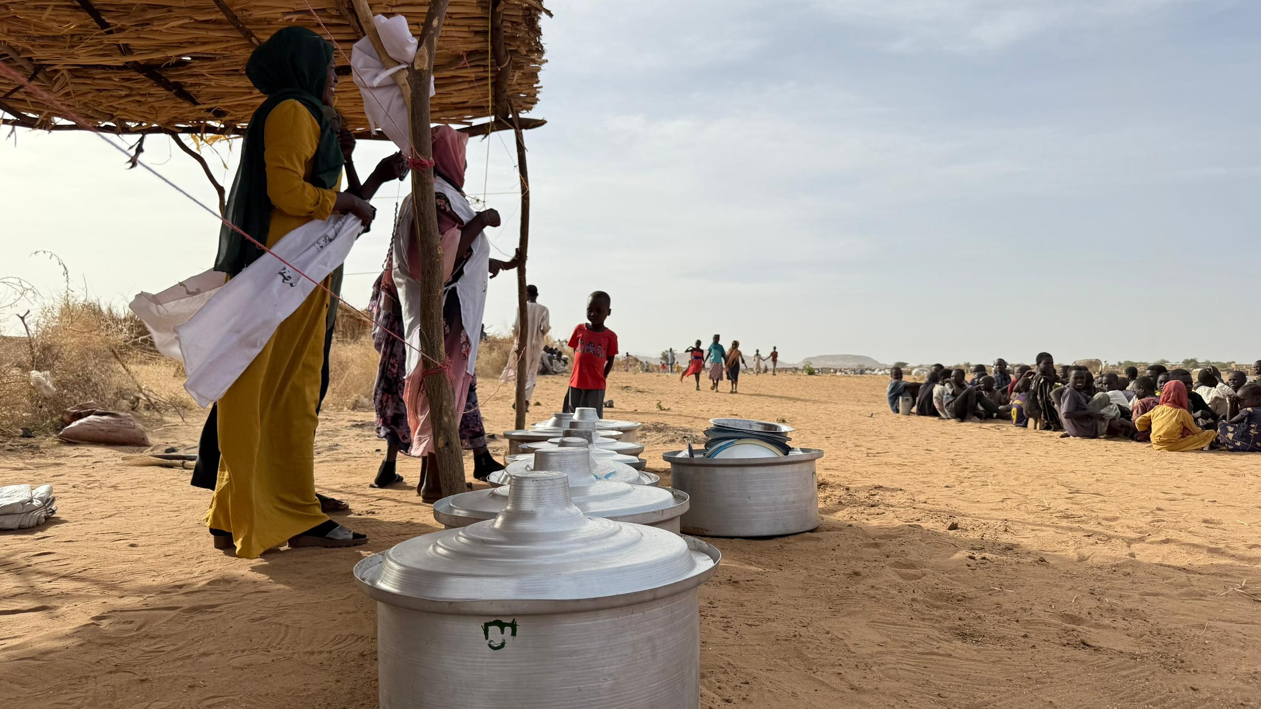 Children gather at a community kitchen set up in an open field on the outskirts of Tawila, where many displaced families are sheltering in difficult conditions.