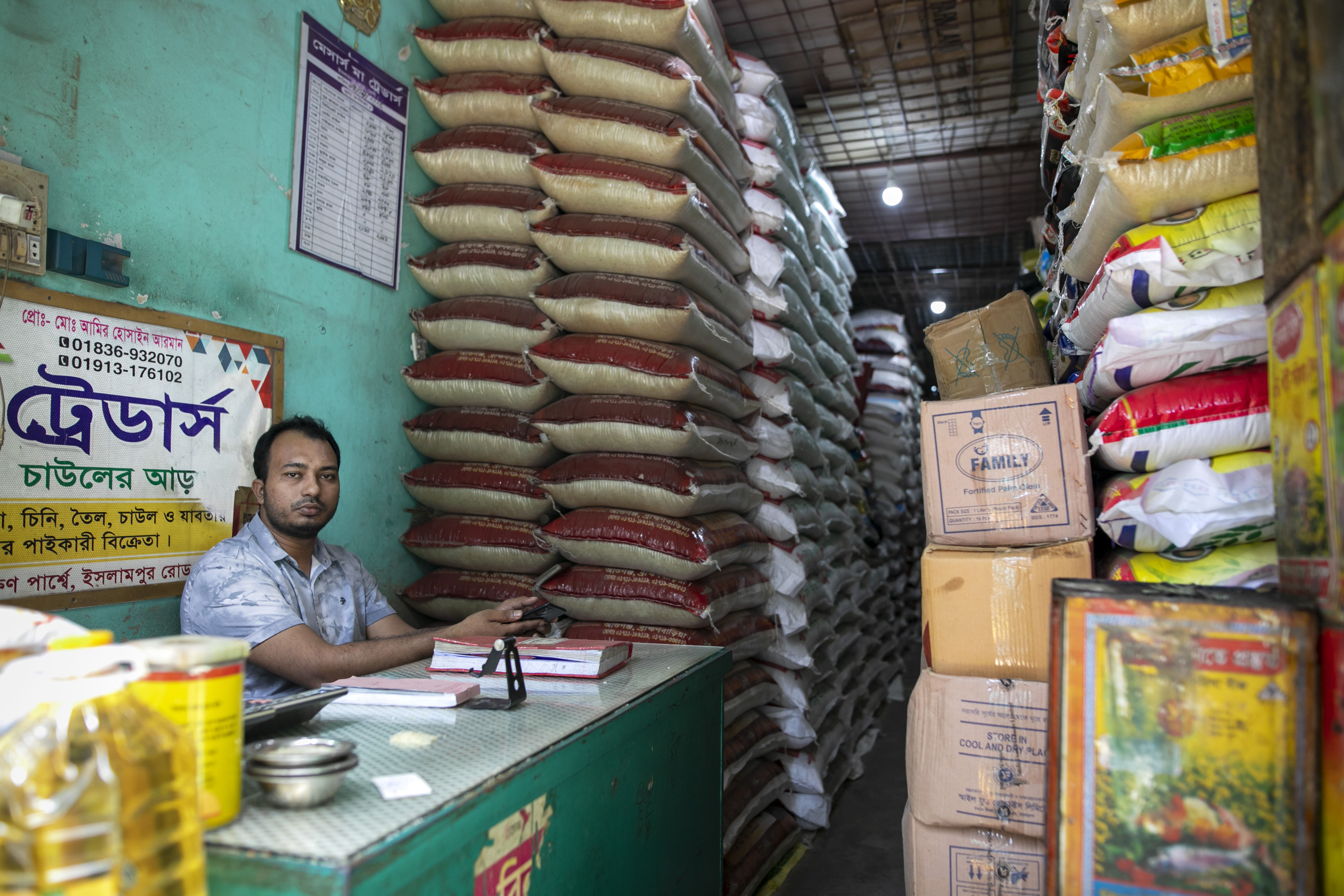 Nazmul Hoq sits inside his shop in Feni on 24 October 2025. How is now having to both buy and sell stock on credit.