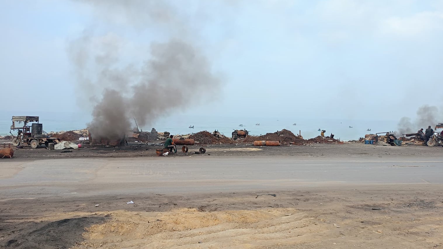 Makeshift fuel refineries expel plumes of black smoke in front of the sea on Gaza's coastal road.
