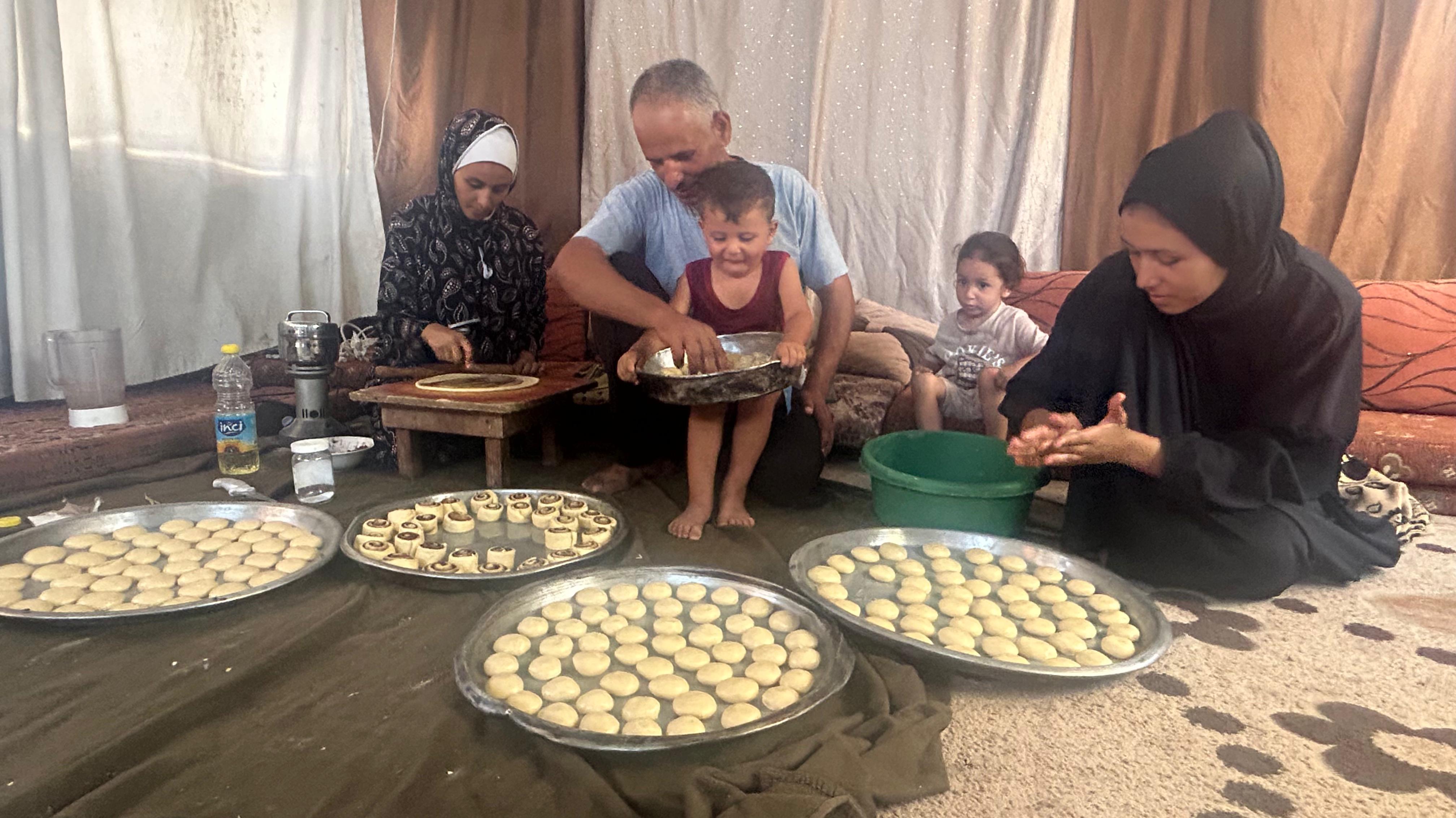 Abu Fadi Karkira with his family in front of the trays of ghoraybeh (butter cookies) made using ingredients provided by Mohamed al-Astal from money donated by a network of readers and friends.