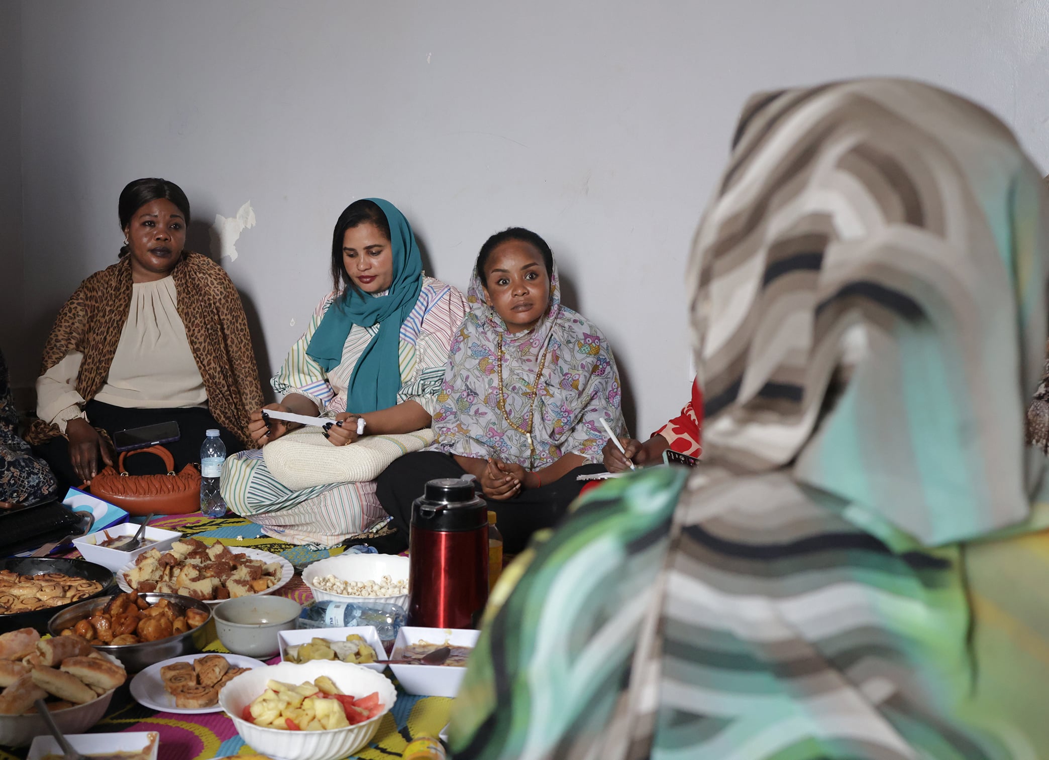 Nusaiba, pictured on the right with prayer beads, listens to a&nbsp;Funjan Niswan participant share a personal story of displacement and refuge.