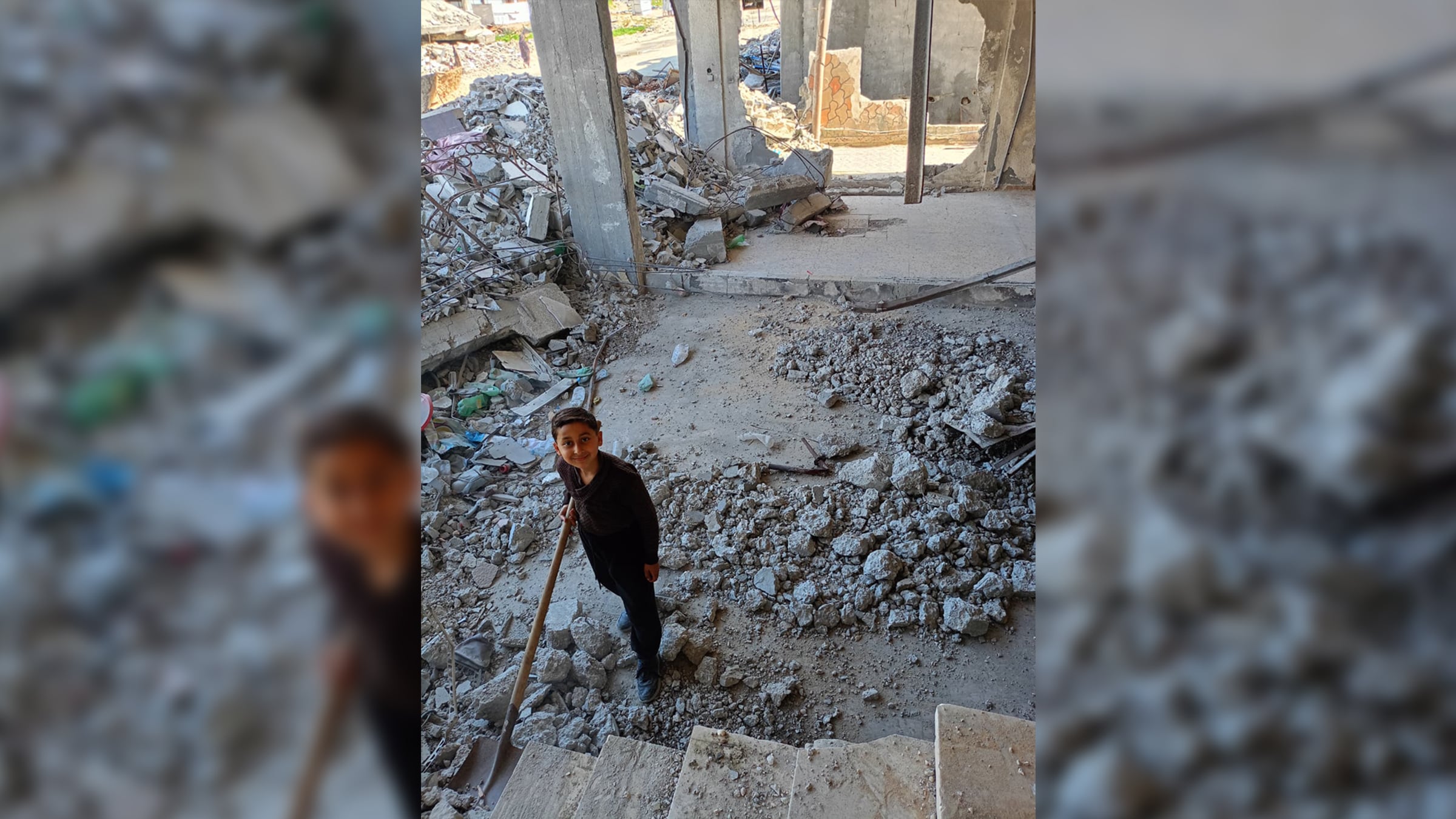 Zine El-Dine, one of Rasha Abu Jalal's sons, helps clear the rubble around their destroyed home.