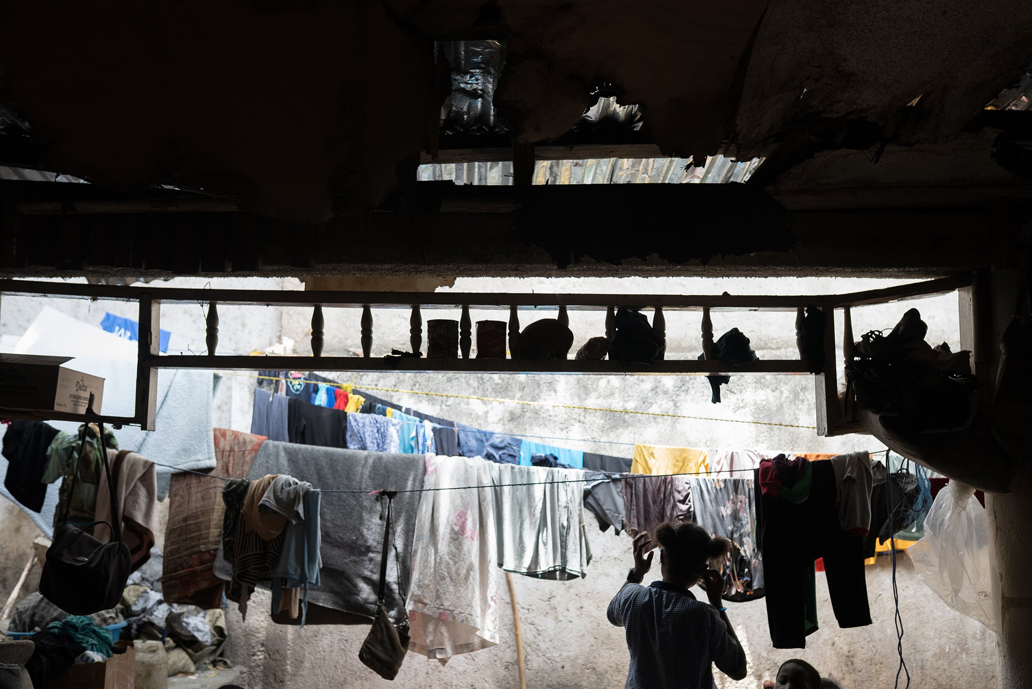 An image showing the shadow of someone hanging clothes at Club International, a former nightclub in Port-au-Prince now serving as a displacement site, June 2026.