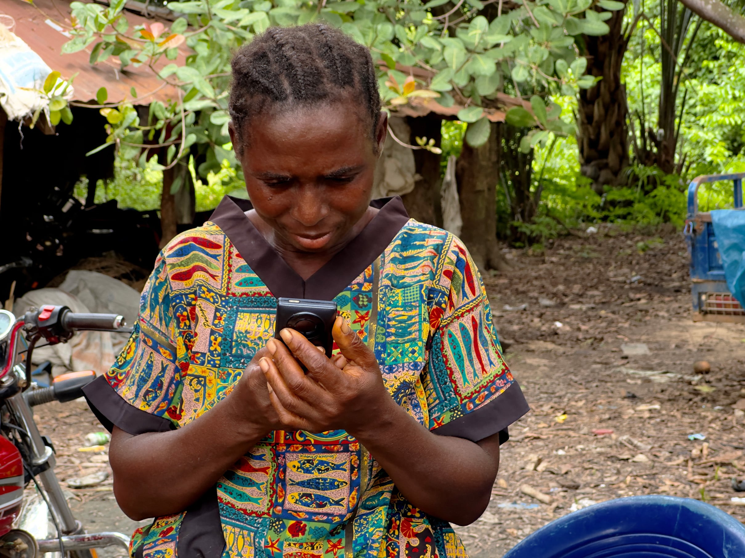 A person is pictured holding a phone with both her hands and looking down at it.