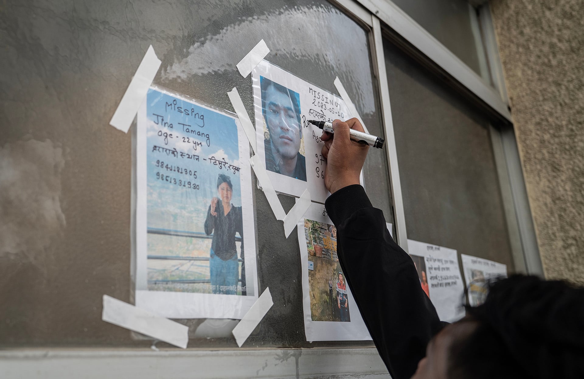 A person writes on a missing person flyer