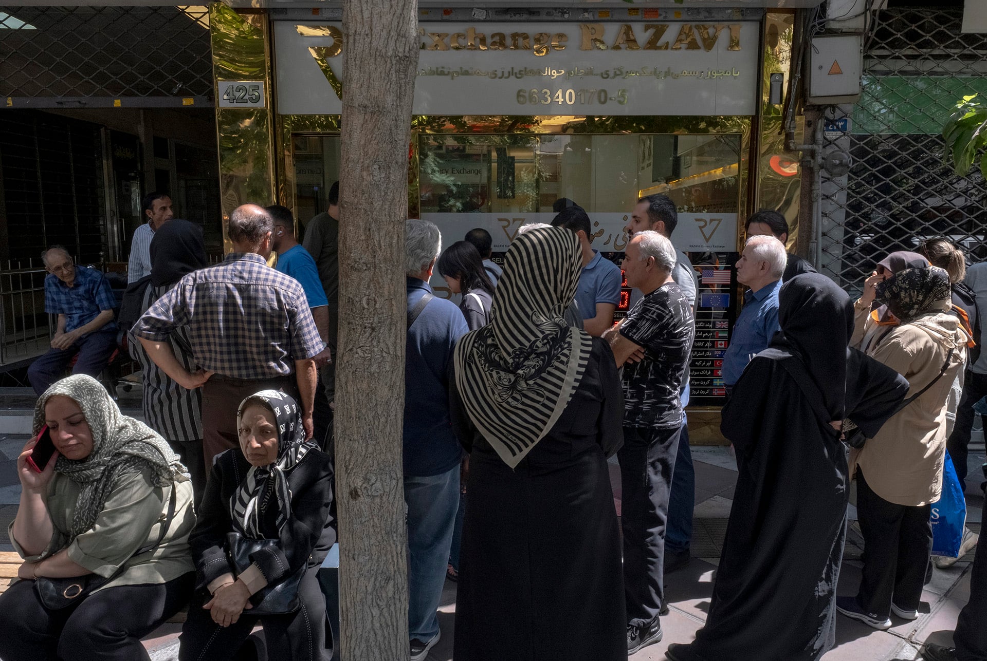 Iranian people gather outside a currency exchange shop in downtown Tehran.