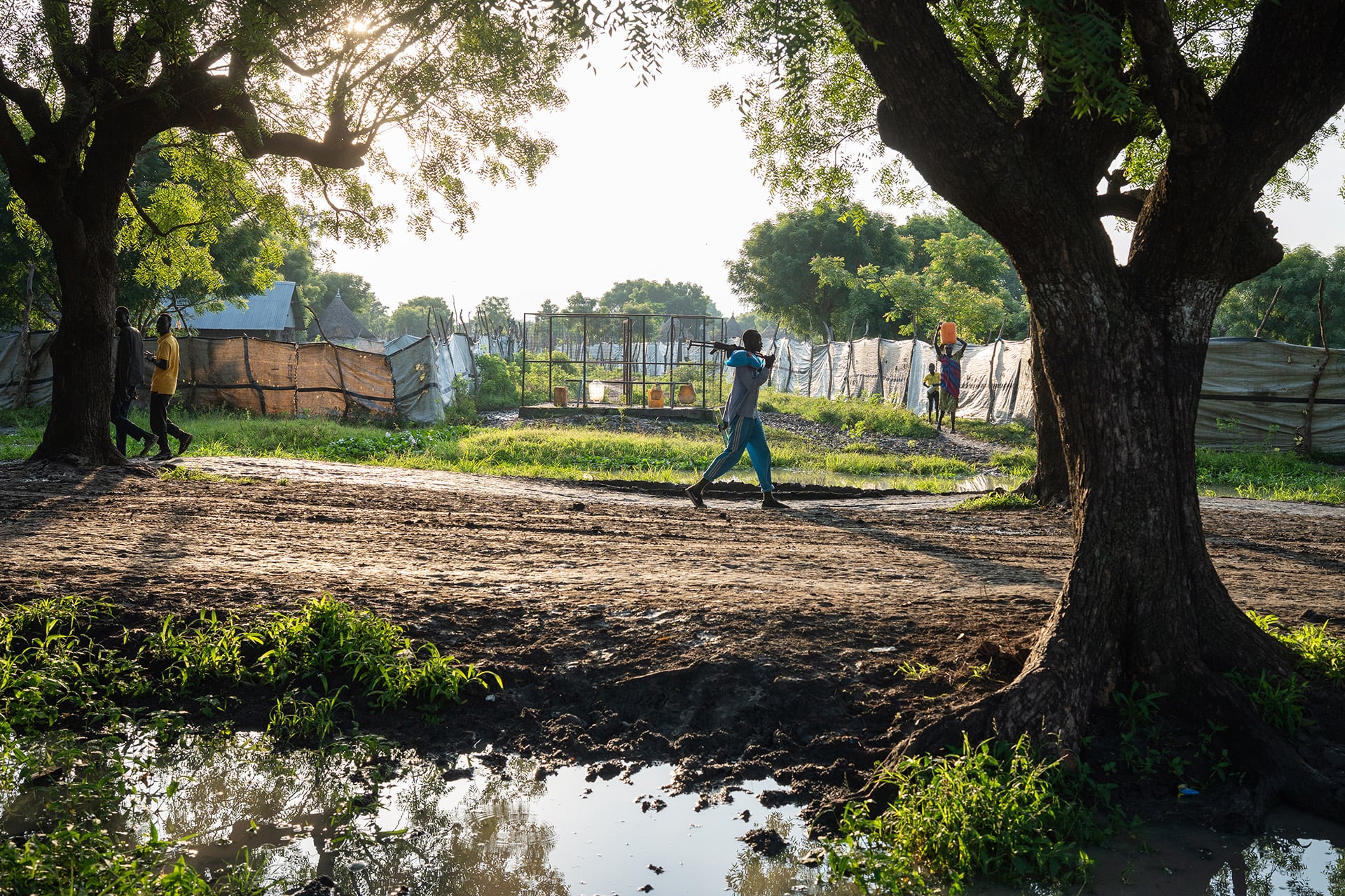 A man with a gun walks along a road in a town