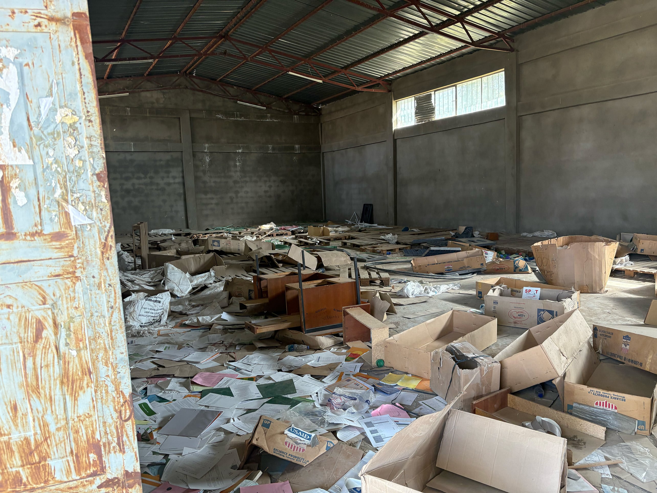 A picture showing boxes of aid opened and looted in a warehouse.