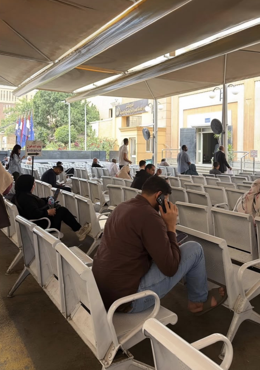 A photo from the Abbasiya Immigration Office in Egypt showing people waiting in chairs.