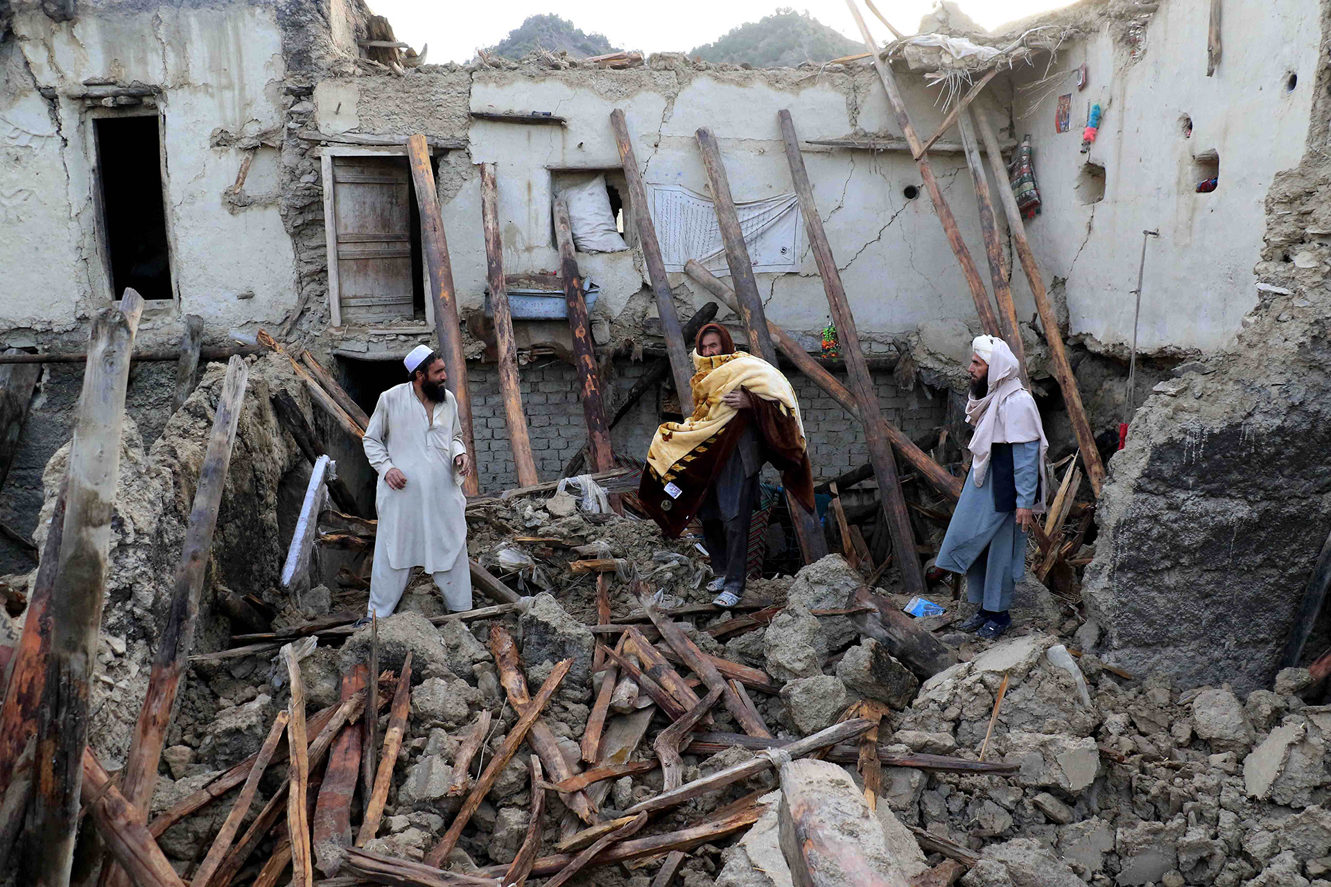 Men in Ochlakai village assess the damage to their home and look for any remaining valuables amid the rubble.