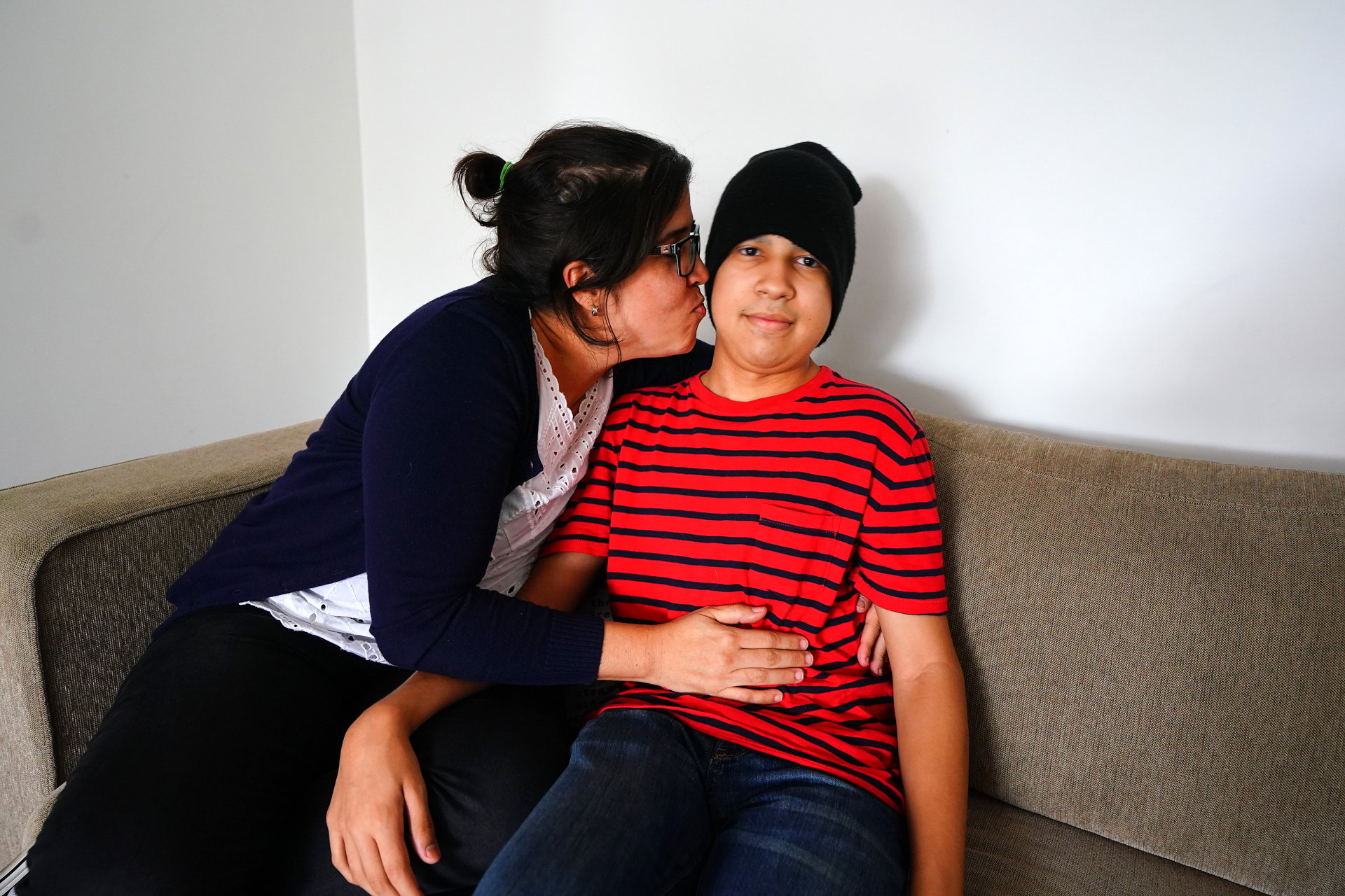 A mother kisses her son on the cheek