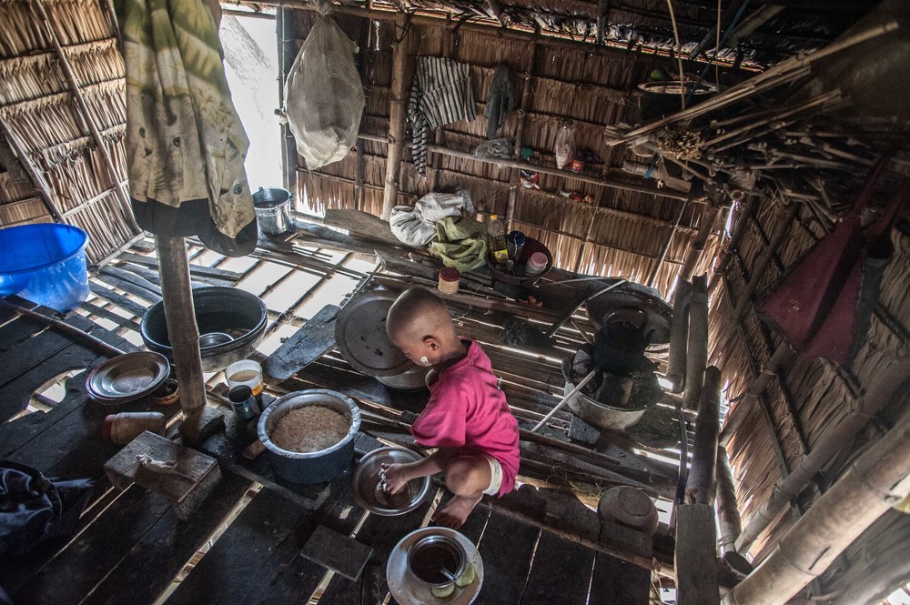 A child is alone in the center of a room helping to prepare food.