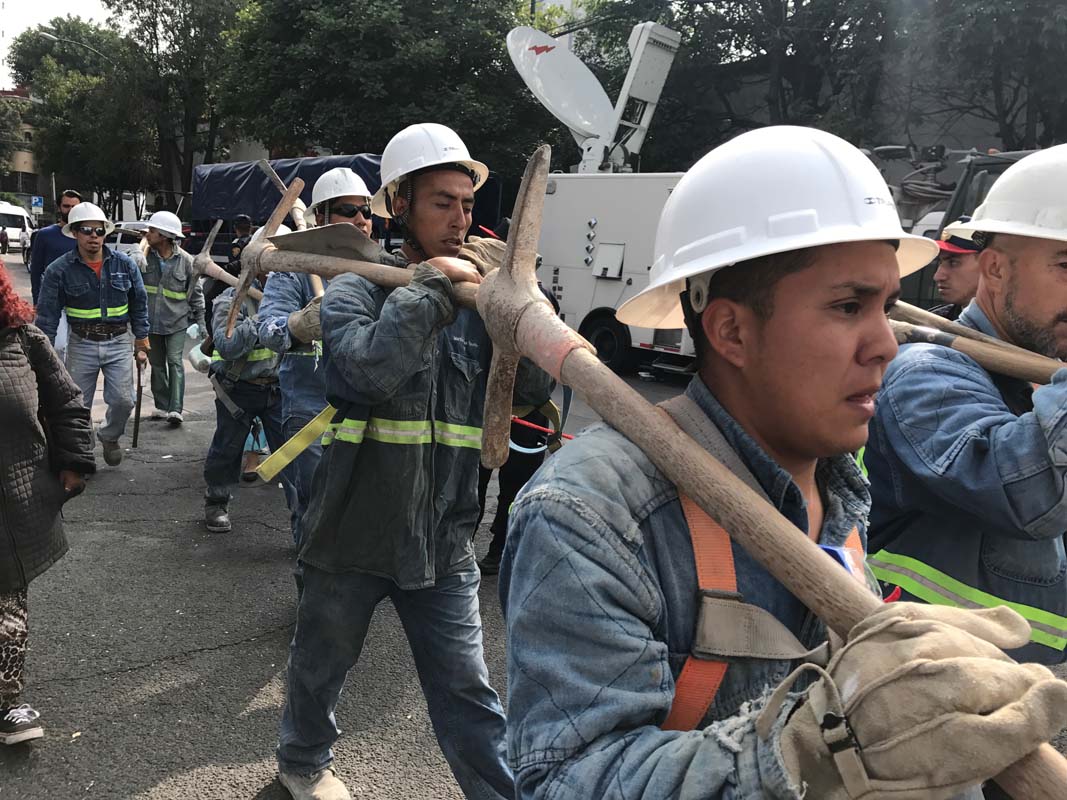 Volunteers with pick axes march down a street in Mexico City's Condesa neighborhood after the earthquake.