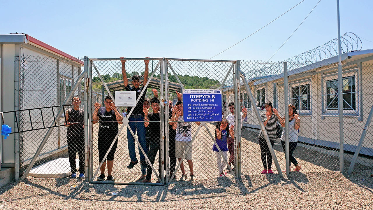 A group of Syrian and Iraqi refugees behind a fence