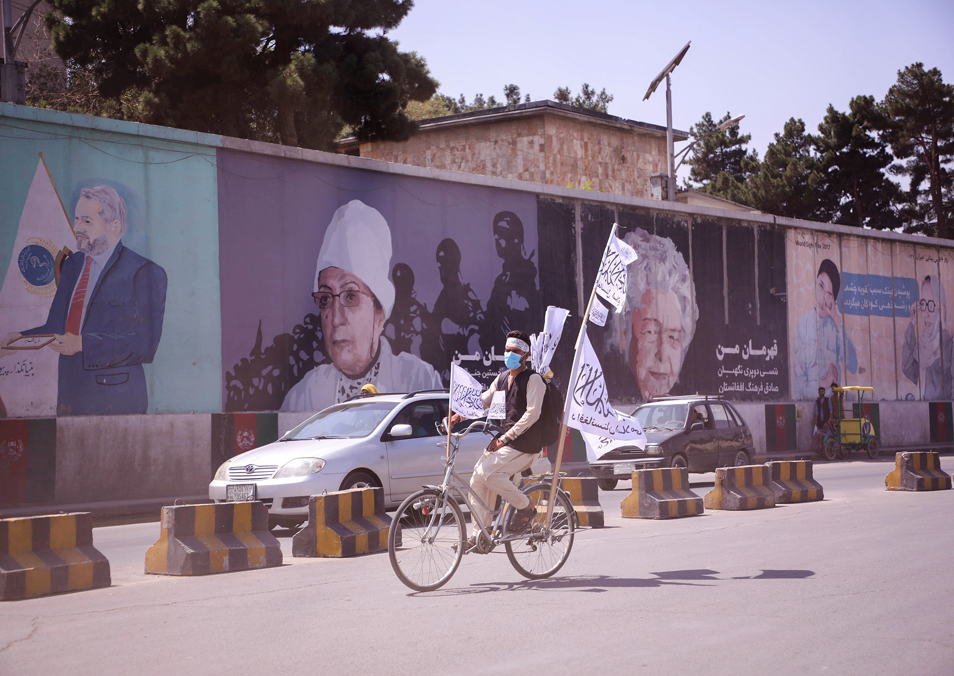 An Afghan man rides a bicycle carrying Taliban flags through the streets of the capital, Kabul, on 2 September 2021.