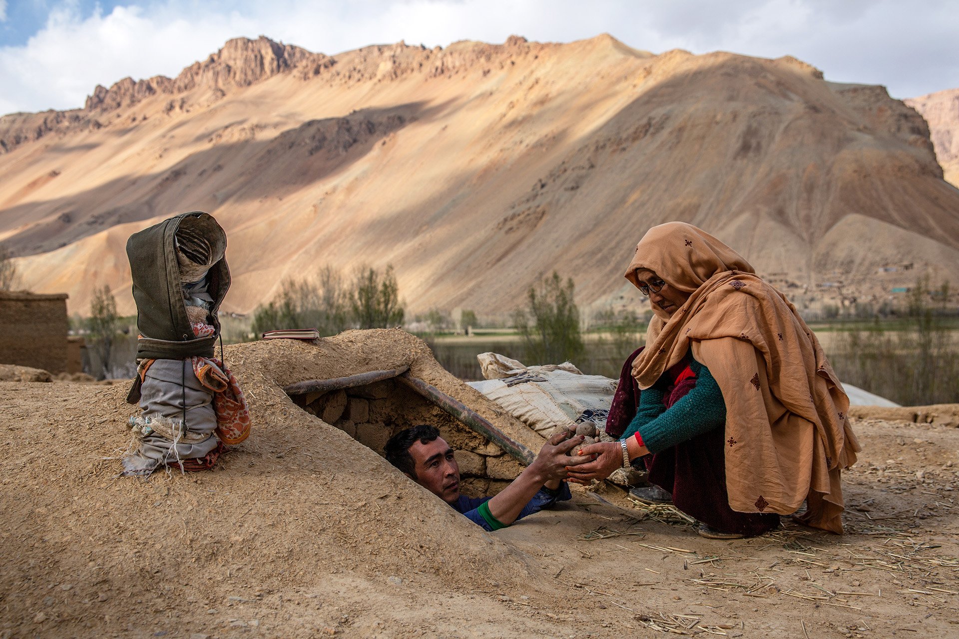 Roqia Qasqari, 47, who lives in Gero village in Afghanistan's Bamyan Province, inspects potatoes stored after the previous harvest. Snow was scarce over the winter, raising fears of a severe drought during 2021.