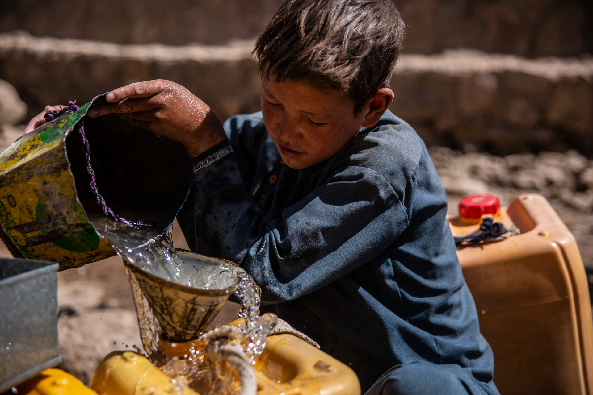 A young boy in Afghanistan pours water